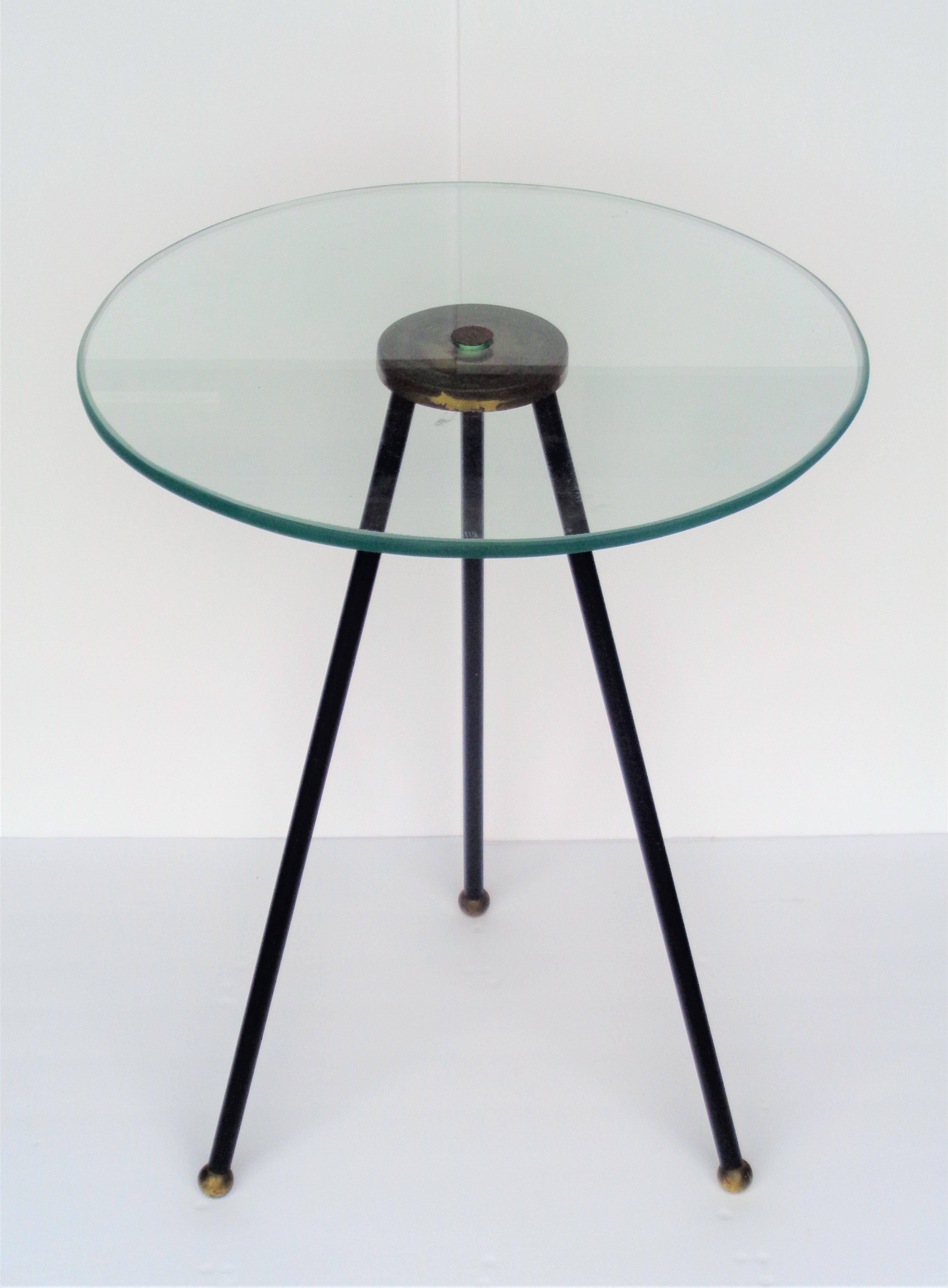 Iron leg tripod table with brass ball feet. The three splayed iron legs are welded at top to a central circular brass disc that screws into and supports a beveled plate glass top. Great looking sleek modernist design in the style of Gio Ponti. Circa