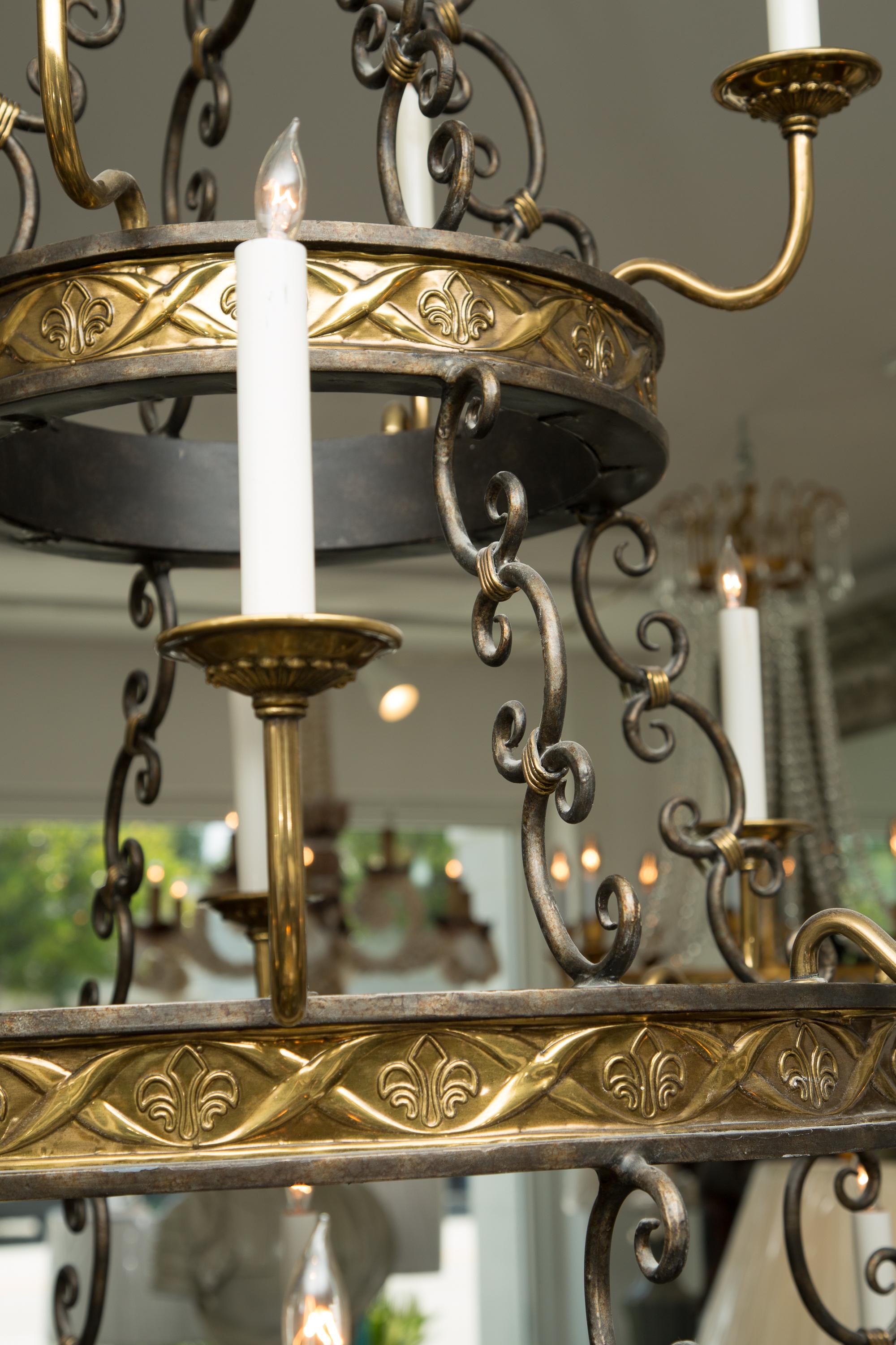 This is a very imposing 20-light iron and brass chandelier in the form of three descending graduated concentric circular frames with emanating candle arms, terminating in a scrolling frame with centralized finials, 20th century.