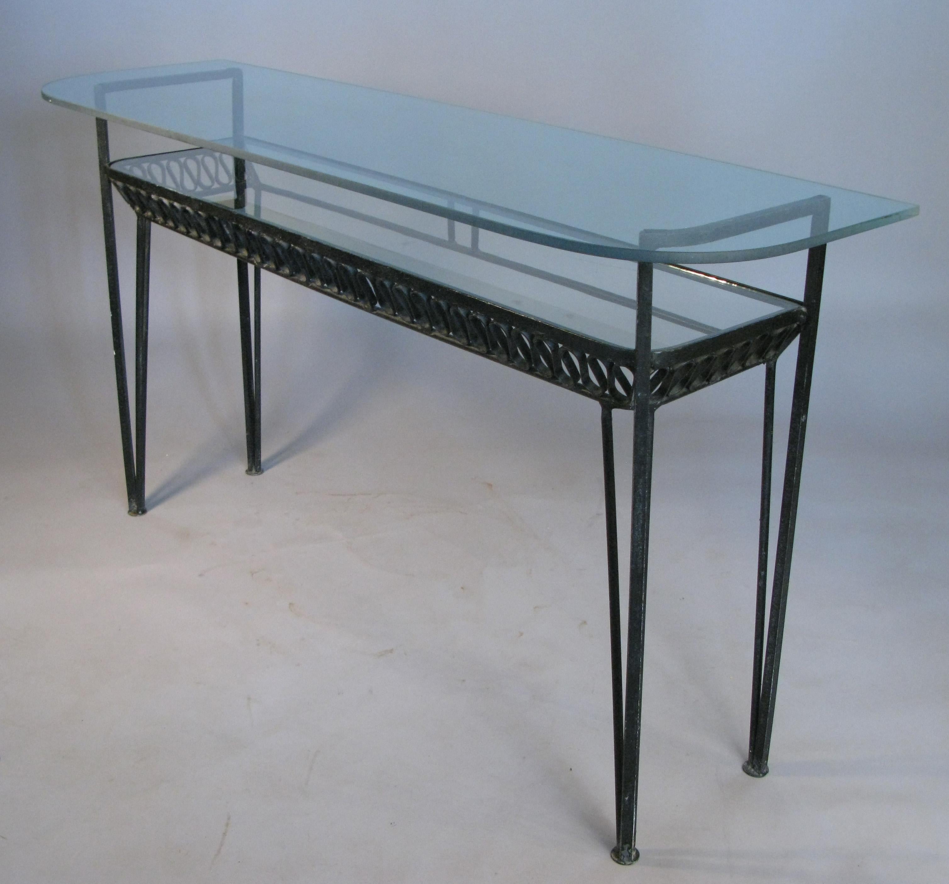 A rare 1950s wrought iron double shelf console table designed by Maurizio Tempestini for Salterini, with two long glass shelves and Tempestini's signature iron ribbon design under the lower shelf.