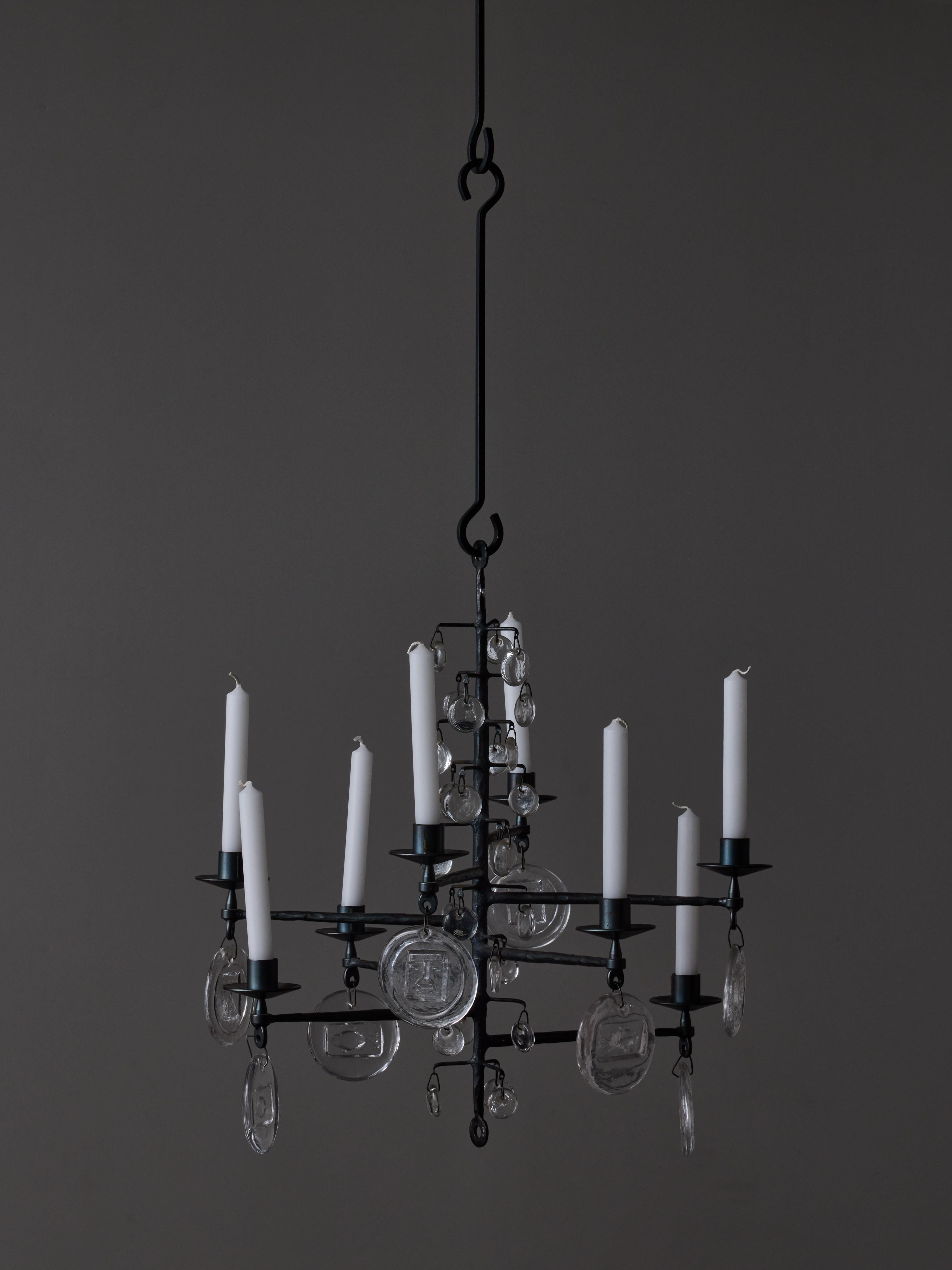 Classic example of Erik Höglund work is this rough iron chandelier made of eight arms of light from which hang glass tassels with various molded decors .
As always with the chandeliers from Höglund, this piece made by Kosta Boda isn't meant to be