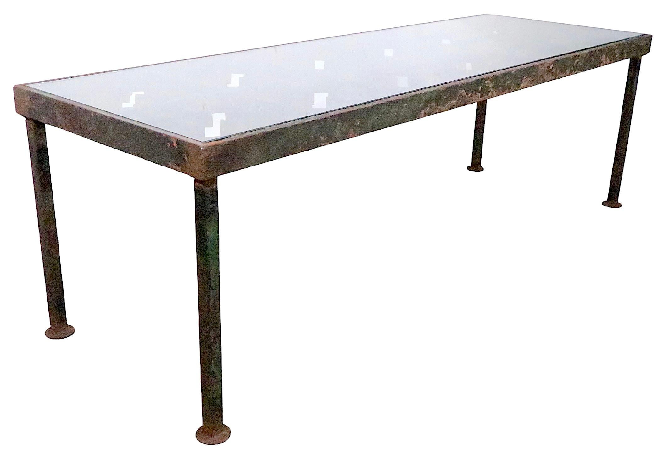 Well crafted garden, patio, indoor/outdoor coffee table composed of steel, cast iron and plate glass. The table top is a section of  ( very ) heavy cast iron, salvaged from an old building, in a heavy steel frame and squared steel legs. The top is a