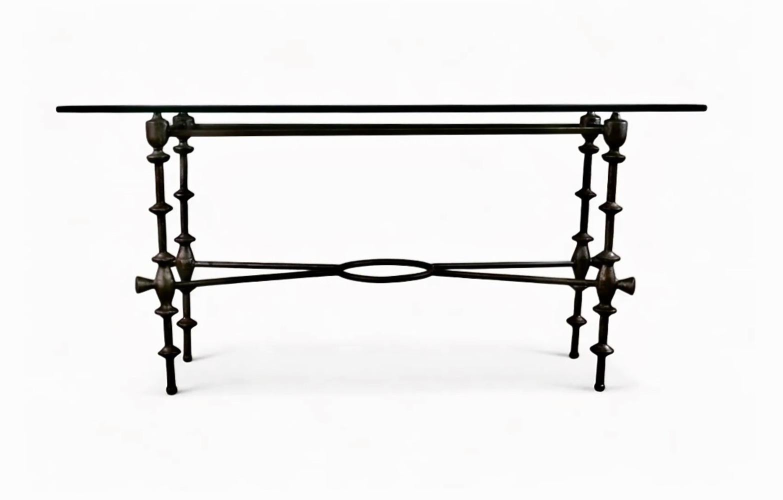 This is a very chic and desirable console or sofa table created in the style of Giacometti. It is topped with a thick dark tinted glass panel. Giacometti-style tables are very desirable and are suited for placement in modern, as well as antiques