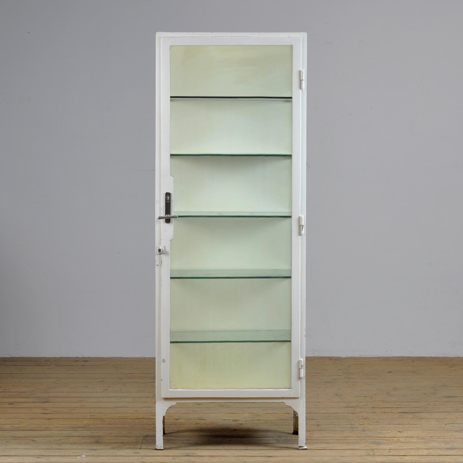 Medical cabinet from the 1930s. The cabinet is produced in hungary and is made of thick iron and antique glass. With the original glass shelves of 8mm thick. The glass plates have a green tint. The lock and handle are also original and functional.