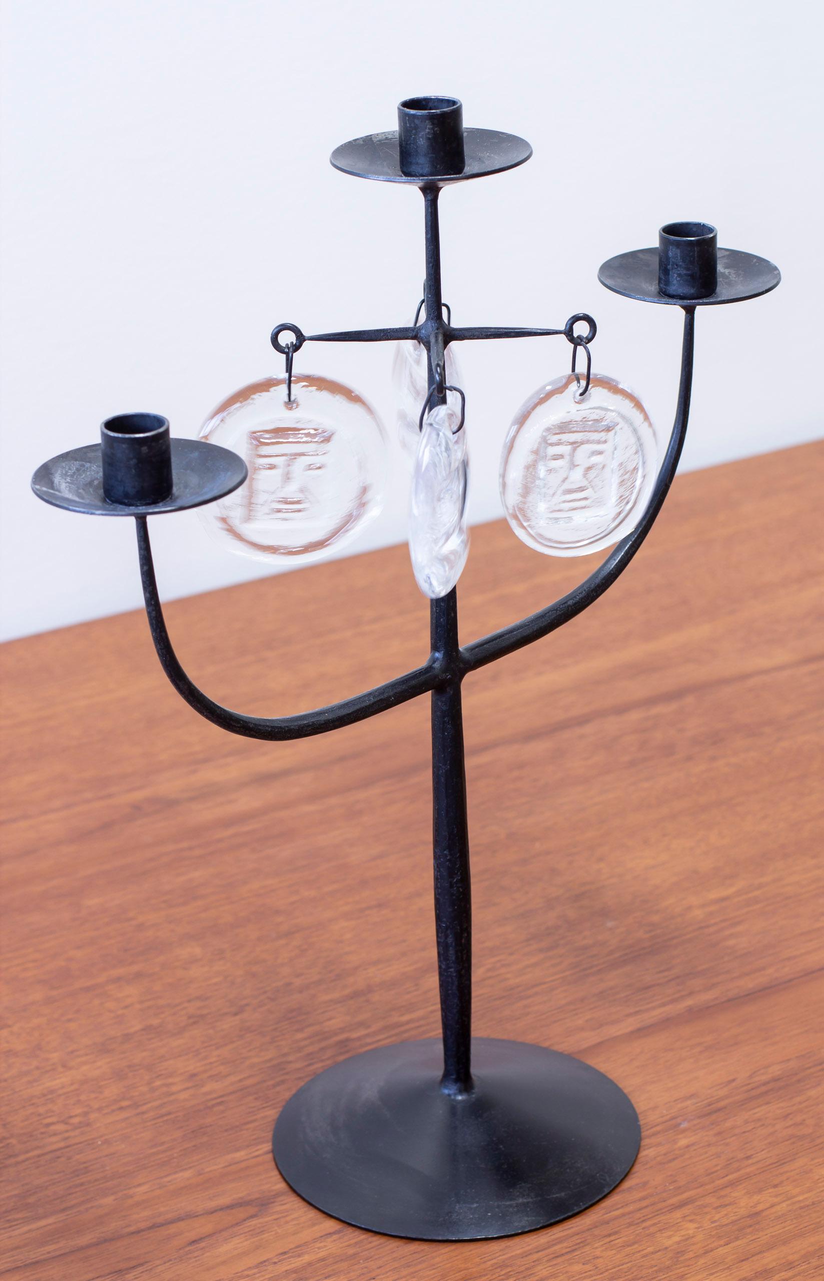 Three armed candelabra designed by Erik Höglund. Hand made during the 1950s by Boda Smide in Sweden. Wrought iron and mold blown clear glass prisms with patterns of people and fishes. Very good vintage condition with age related wear and