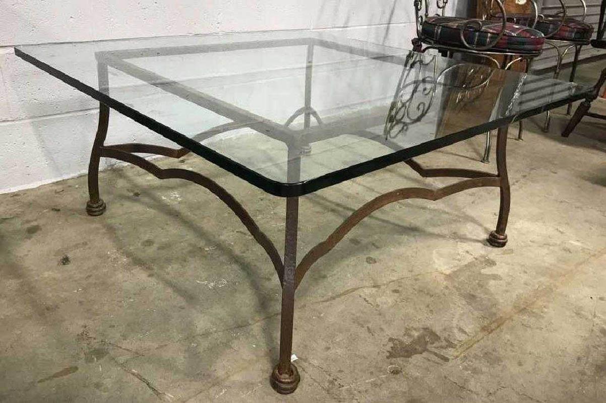 Indoor or outdoor iron and glass coffee table has hand-forged structure and legs. Tabletop is square with rounded corner edges. Rod iron contains some weathering.