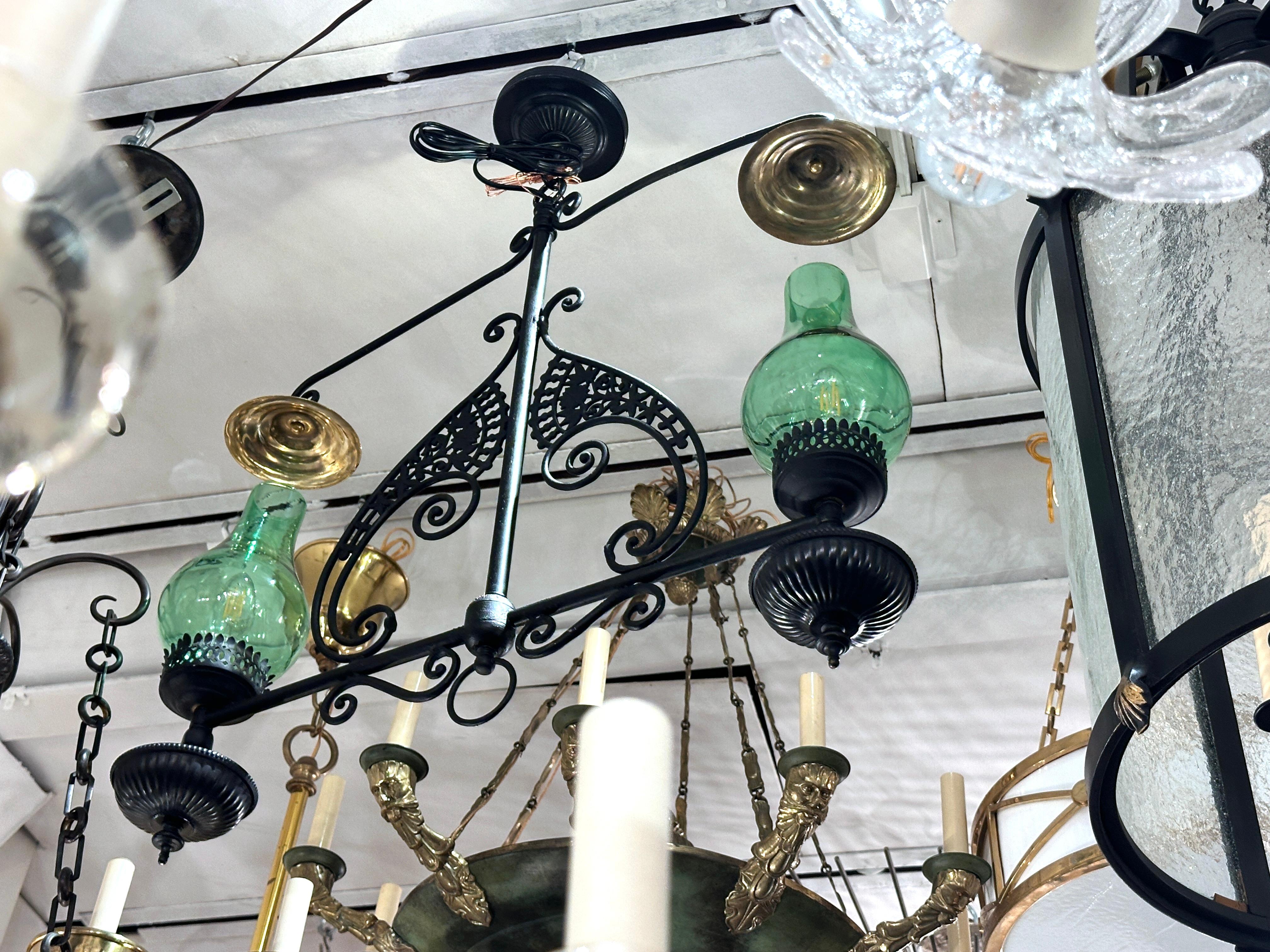 A circa 1940's French hammered metal light fixture with foliage motif and green glass hurricanes.

Measurements:
Drop: 26