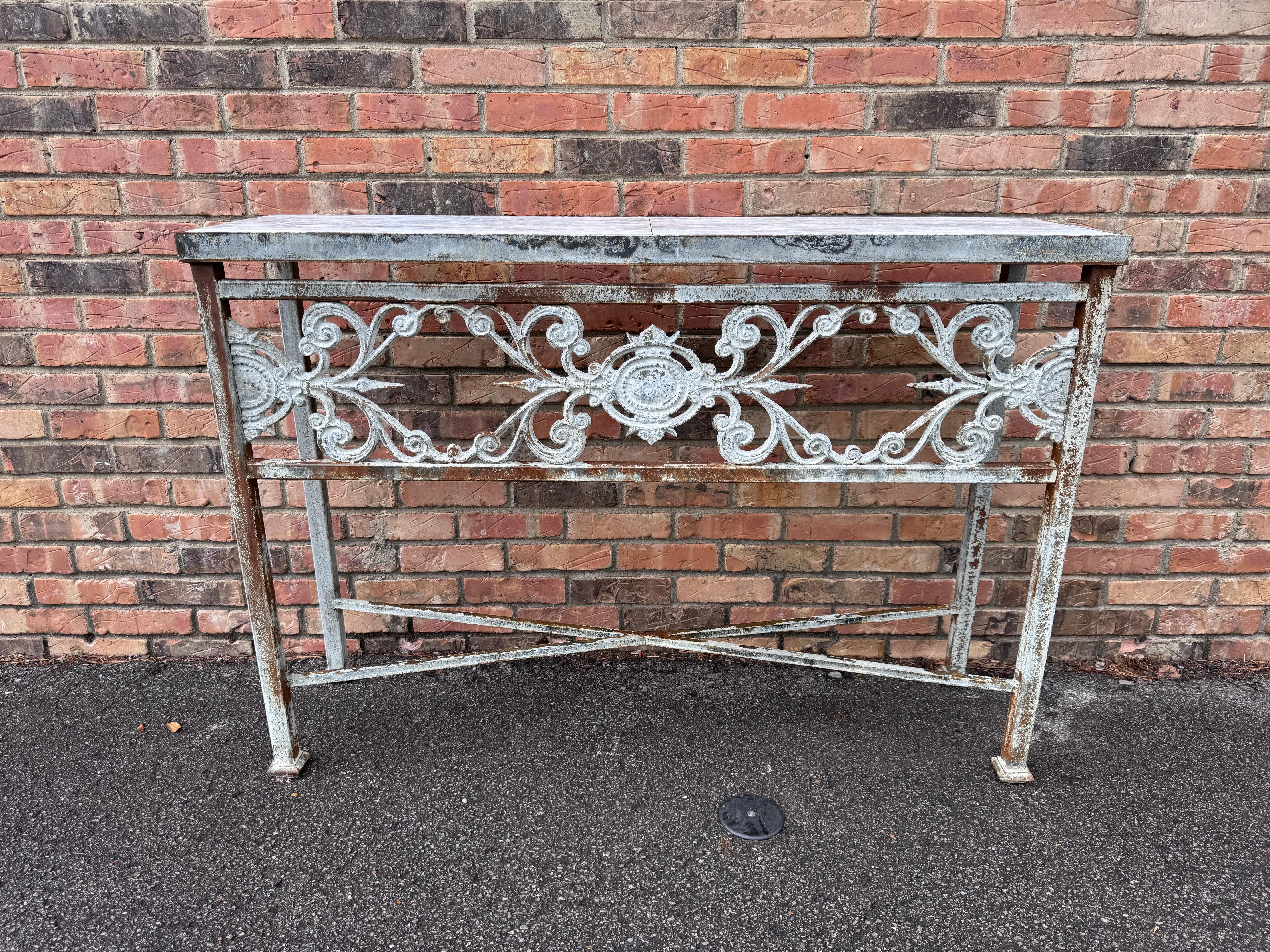 Se trata de una preciosa consola de hierro de fabricación local con un bonito acabado de zinc envejecido, que también cuenta con una tapa de mármol para una versatilidad en exteriores sin necesidad de mantenimiento. Esta mesa permitiría un estilo de