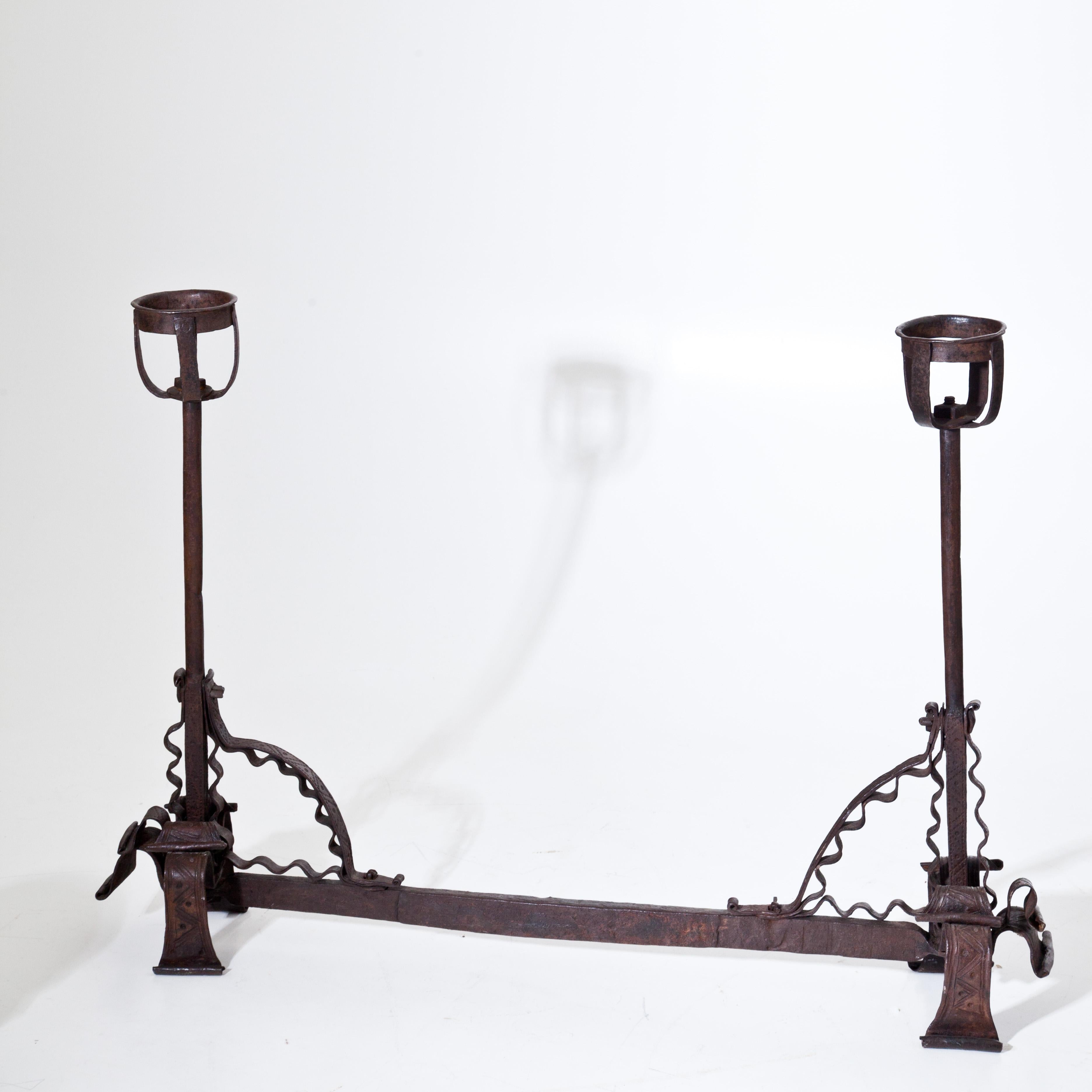 Iron andiron or fire dog with wavy bands and two sockets on the left and right. Beautiful age-appropriate patina.
 