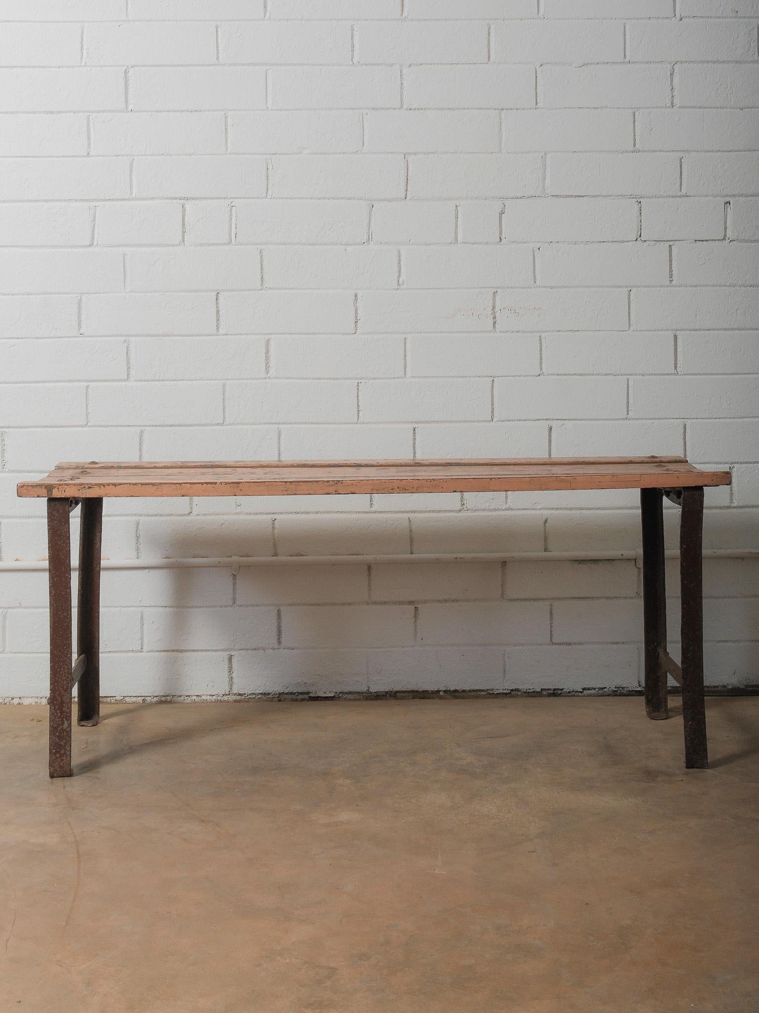 A study in raw materiality, this bench brings together a weathered iron frame and sun-faded timber slats, each surface marked by time and use. The silhouette is understated—straight, functional lines lifted gently by the arched iron legs—yet the