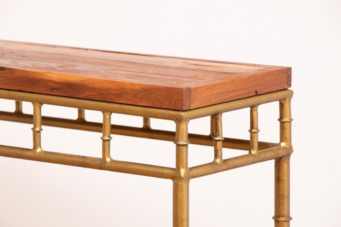 A console table with a contemporary iron base and a reclaimed teak wooden top.