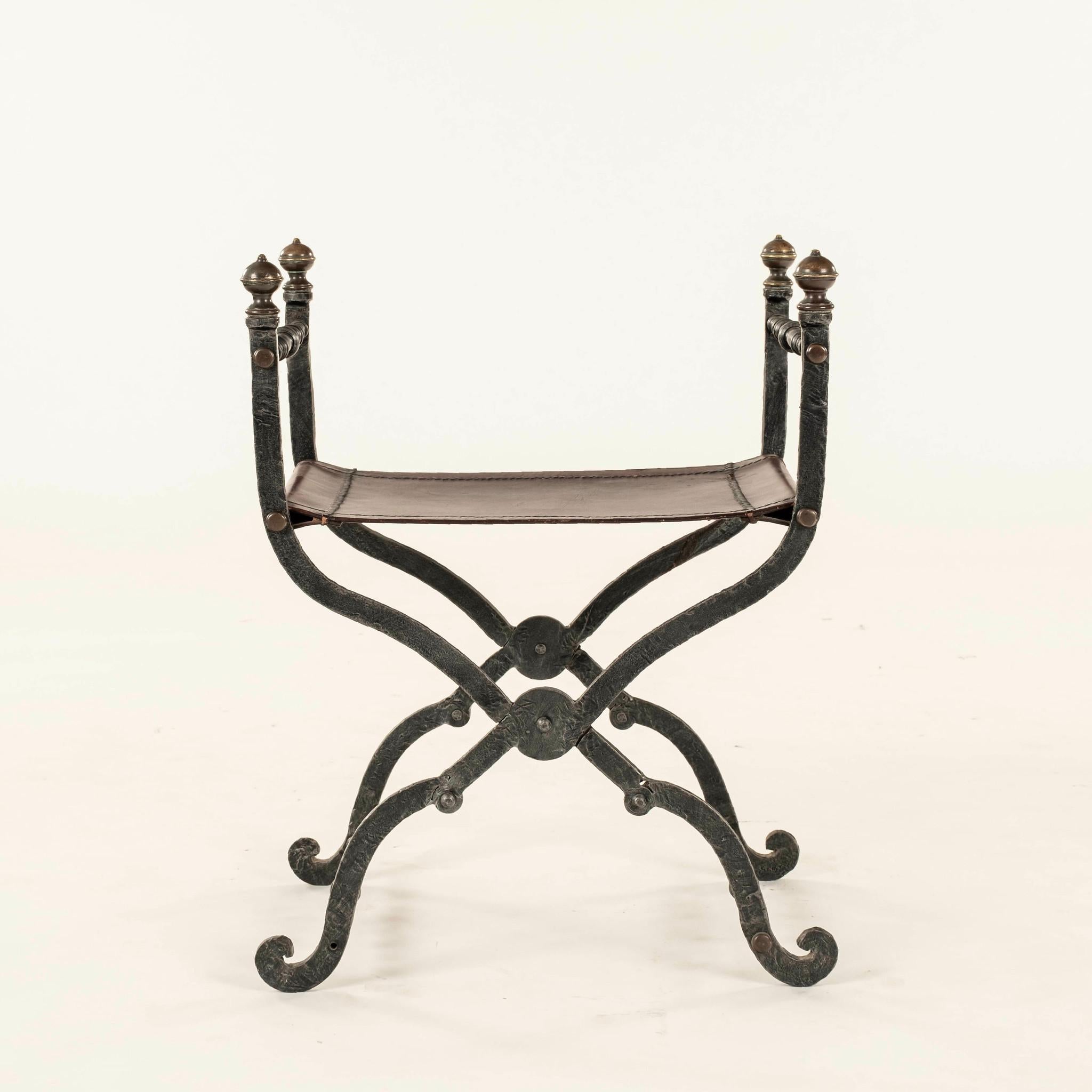 Curule de cuero de hierro español vintage con grandes remates y acentos de latón.