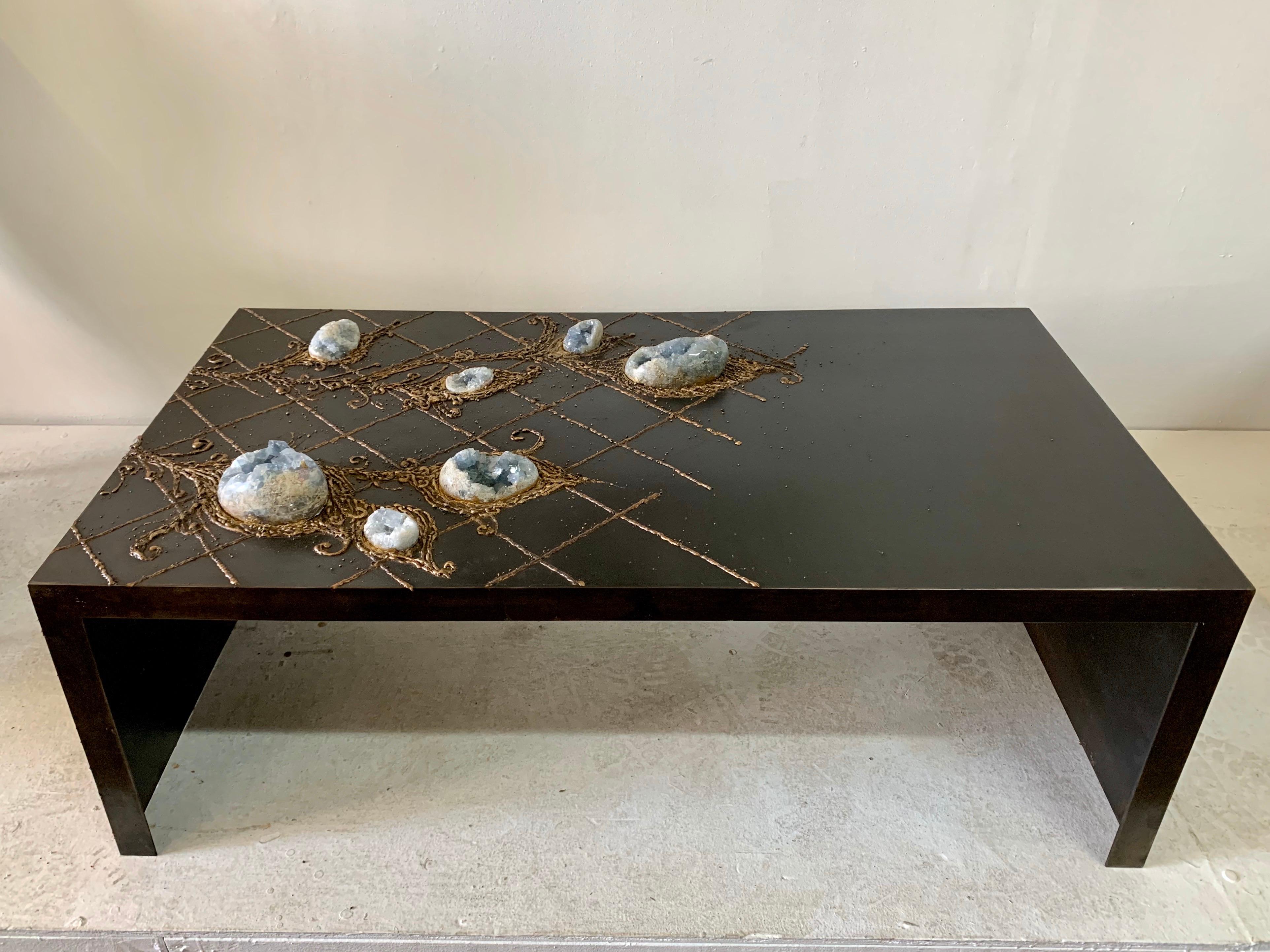 This is a one-of-kind piece. 7 raw celestite geode eggs/ blue crystals embedded in this large and heavy iron coffee table. These natural stone eggs appear like tulip bulbs with an intricate floral bronze embroidered design. This is bronze over