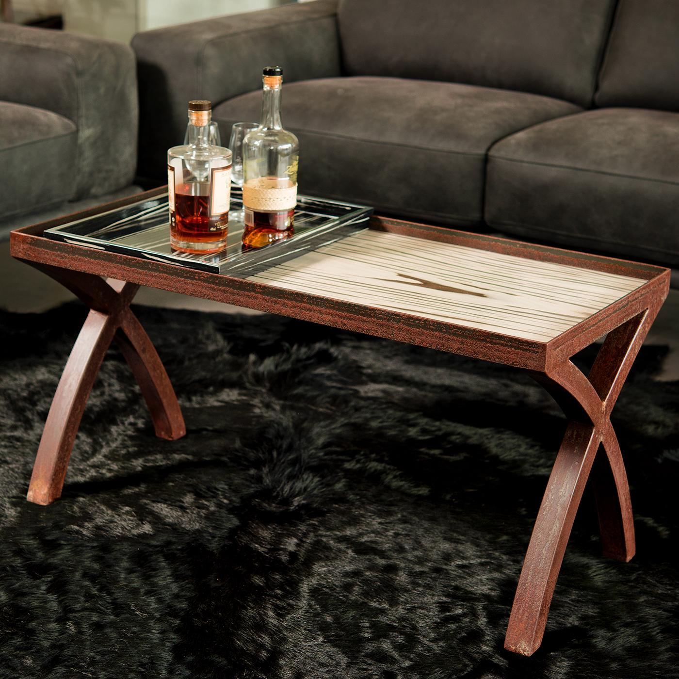 Merging industrial and traditional elements, this coffee table is impeccably crafted by hand. The wood-veneered frame includes two elegantly curved, criss-crossed legs and a rectangular top with raised borders in Corten iron with a captivating