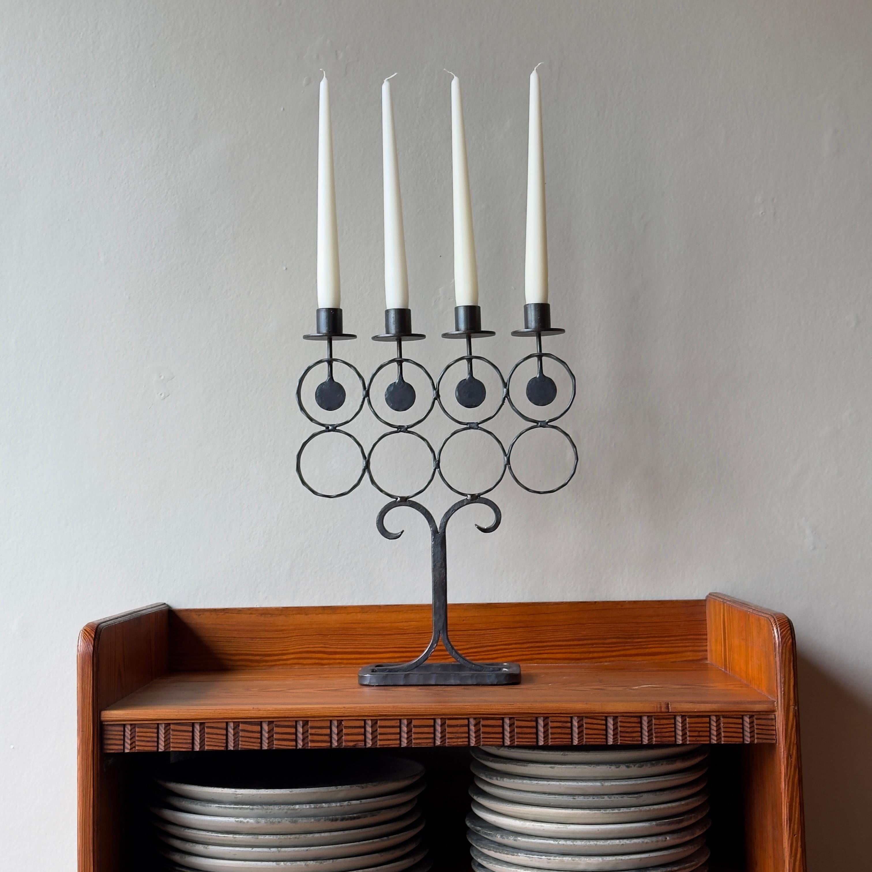 Un candelabro in ferro battuto del designer svedese Bertil Vallien per Boda Smide. 

Otto cerchi formano la struttura di questo semplice design in ferro battuto. Sono collegati al supporto rettangolare dalle estremità arricciate del gambo organico e