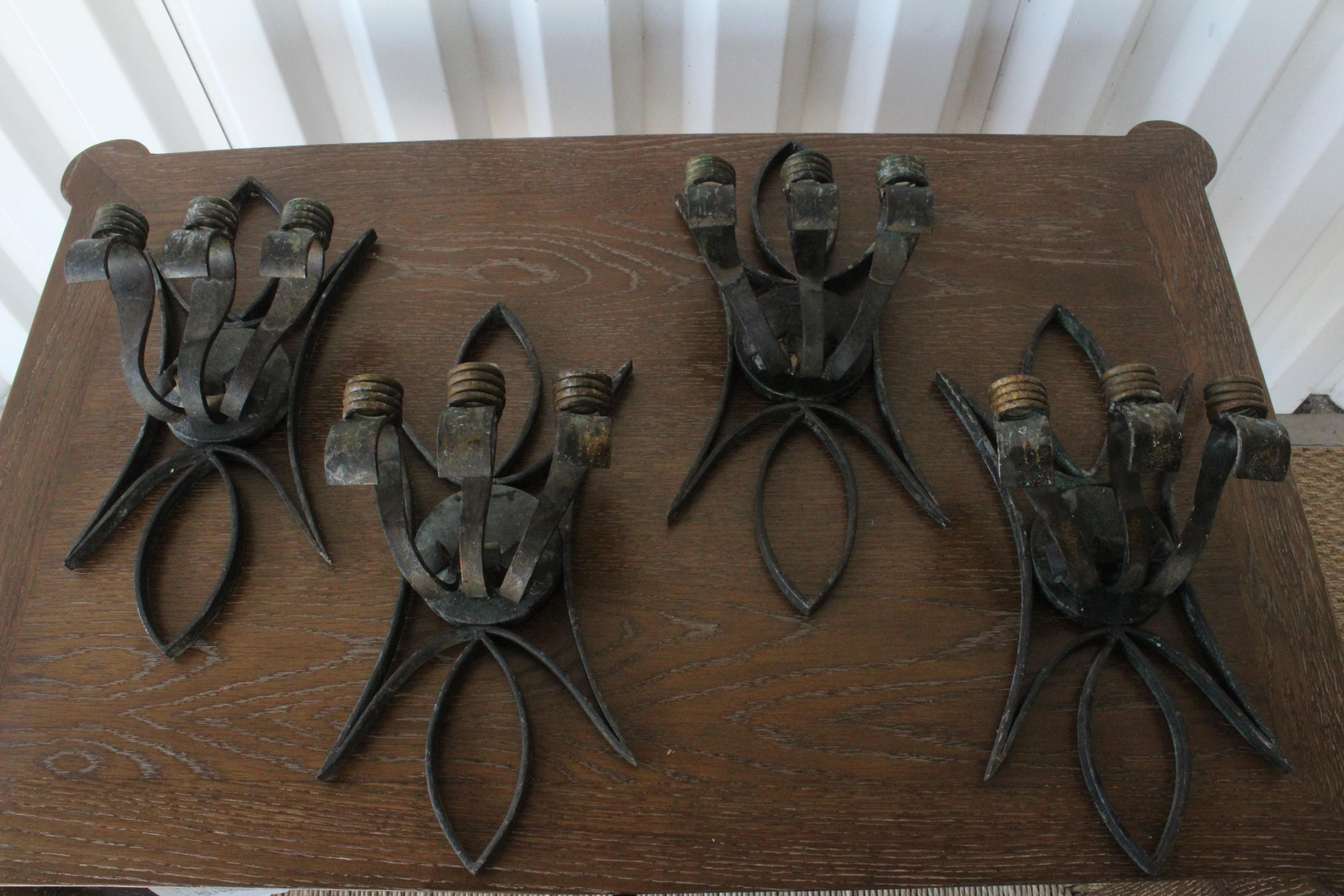 Four iron candle sconces, sold as pairs. From France, 1940s. They show age appropriate patina.