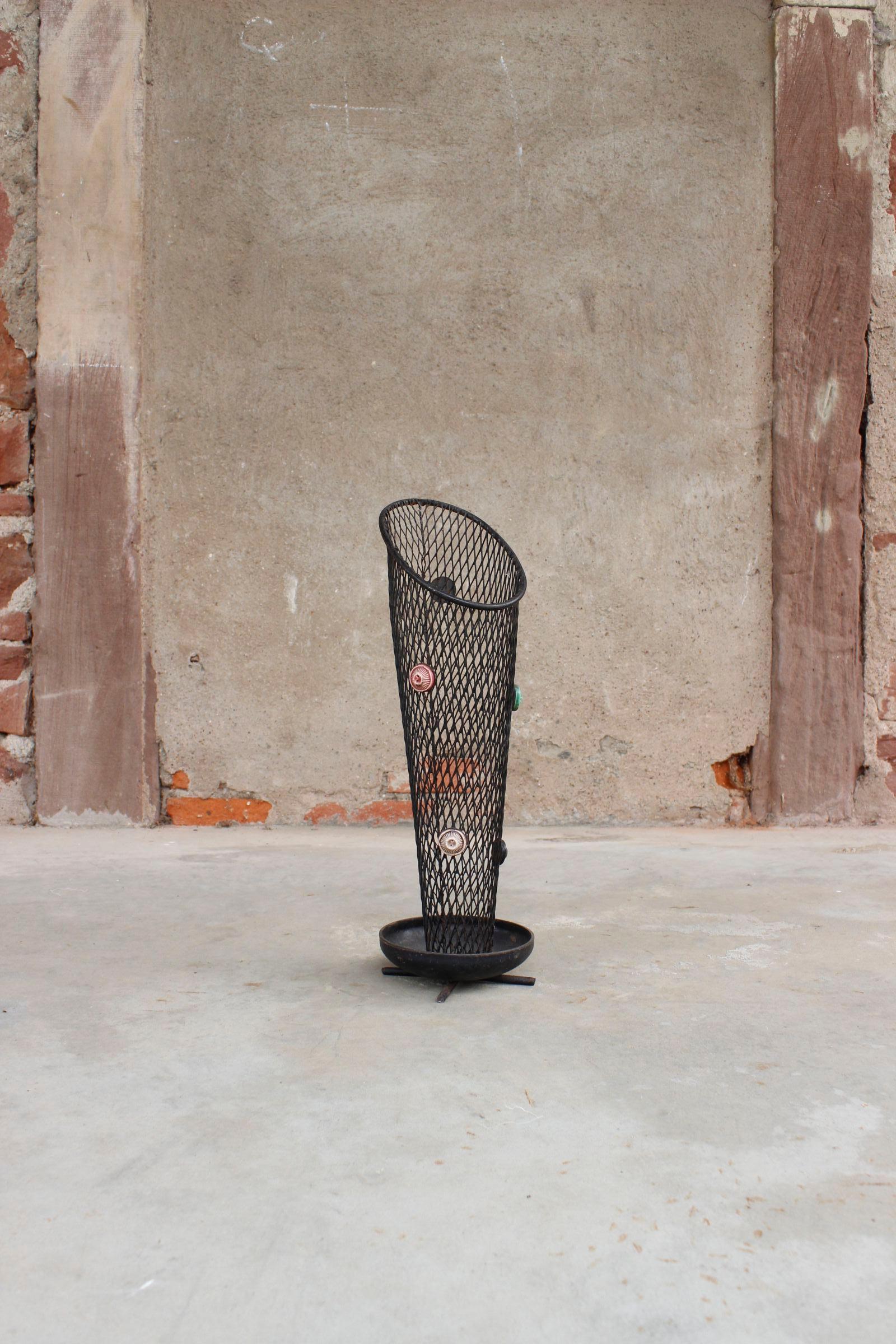 Umbrella stand circa 1950 in the style of Mathieu Matégot, made out of iron painted black and an unfolded perforated sheet adorned with glazed ceramic cabochons. 

I good overall condition, it shows patina consistent with age and use, light wear