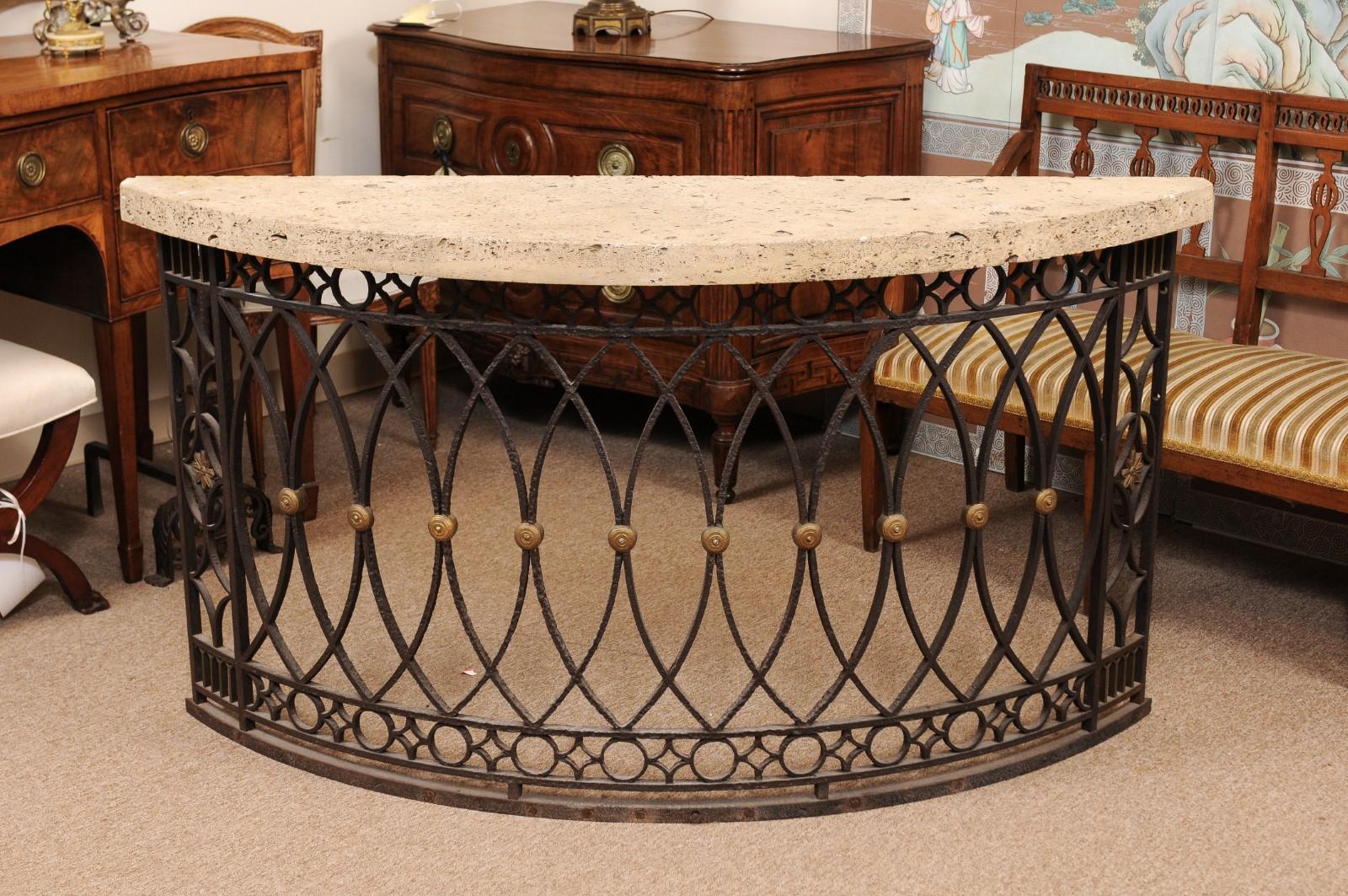 The demilune console table with fossilized stone top above a wrought iron base with interlaced/geometric design and gilt accents.