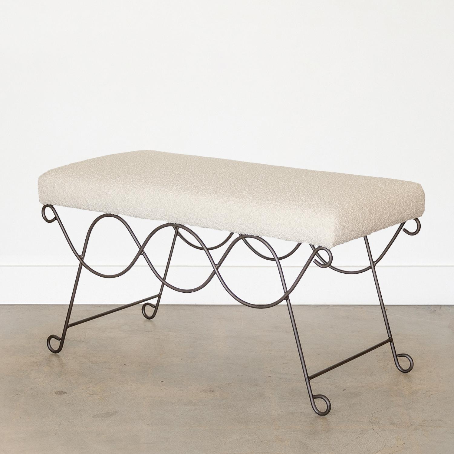 Beautiful iron bench with curved and looped base painted in a matte black finish. Rectangular cushioned seat upholstered in a boucle fabric or can be COM. Multiple available, sold individually.