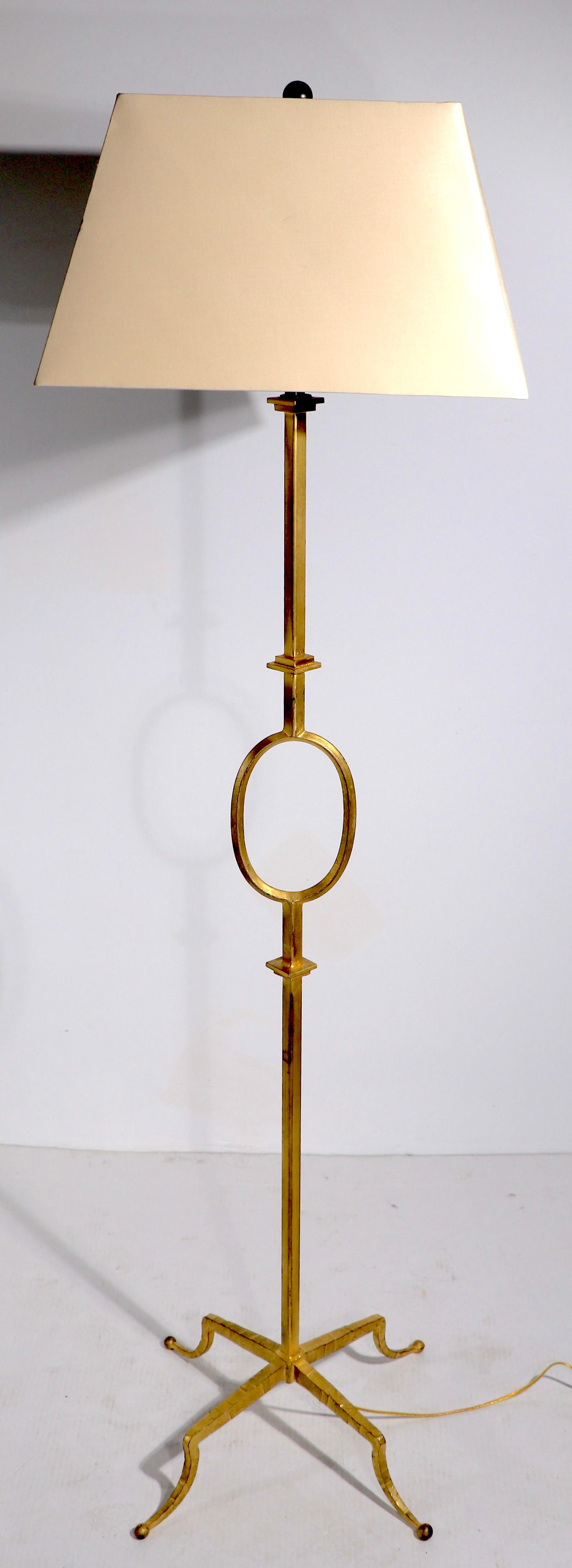 Stylish floor lamp in the style of Gilbert Poillerat. The lamp has a gold pint finish, over hand wrought iron on four legs base. In very good, clean, original and working condition, shade not included. Probably American made in the French style,