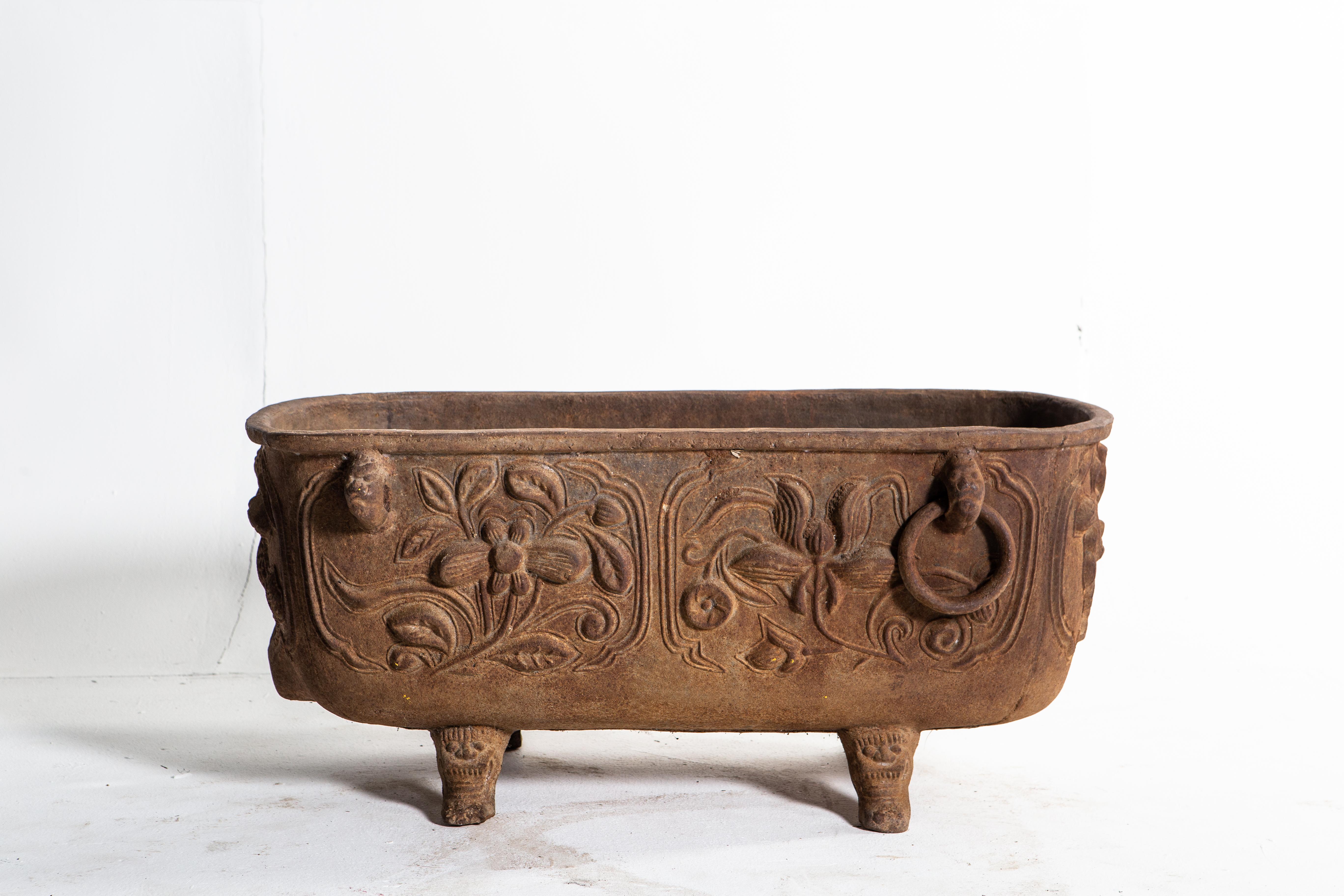 This impressive cast iron flower pot fittingly depicts floral motifs. At nearly three feet in length, the piece is a practical addition to a home garden.