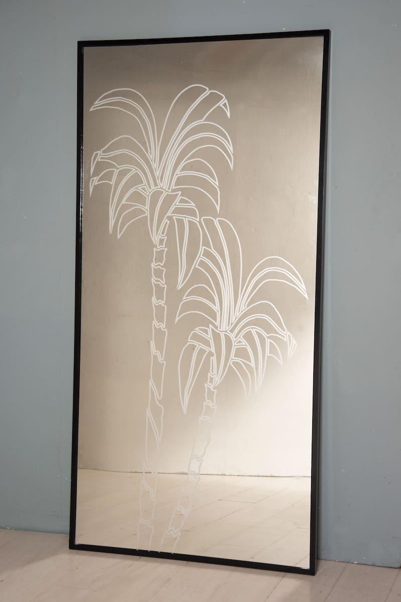 Miroir avec cadre en fer (forme L 3 x 3 cm) laqué noir et miroir fumé (effet gris).

La surface en miroir a été décorée d'un motif de deux palmiers à l'aide de la technique du sablage.

Ce spécimen mesure H 200 x 100 cm .

Il est possible d'avoir la
