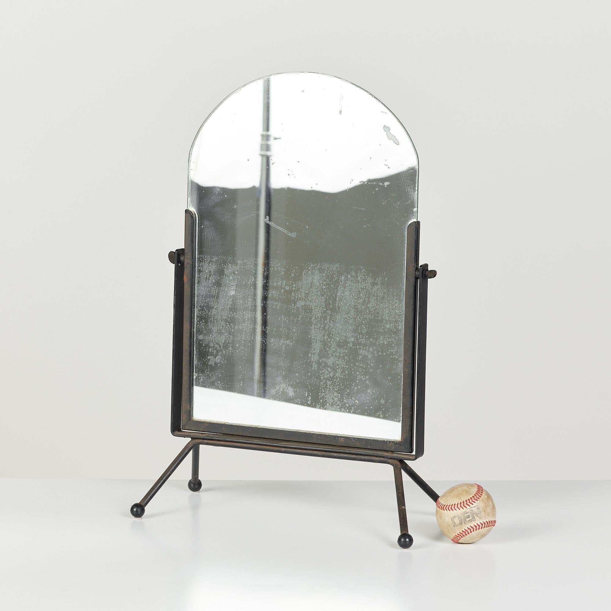 Iron vanity mirror features a curved piece of glass inset in an iron frame. The mirror is set in a swivel frame to adjust your angle and rests upon four splayed iron legs with ball feet.

Dimensions: 13.25