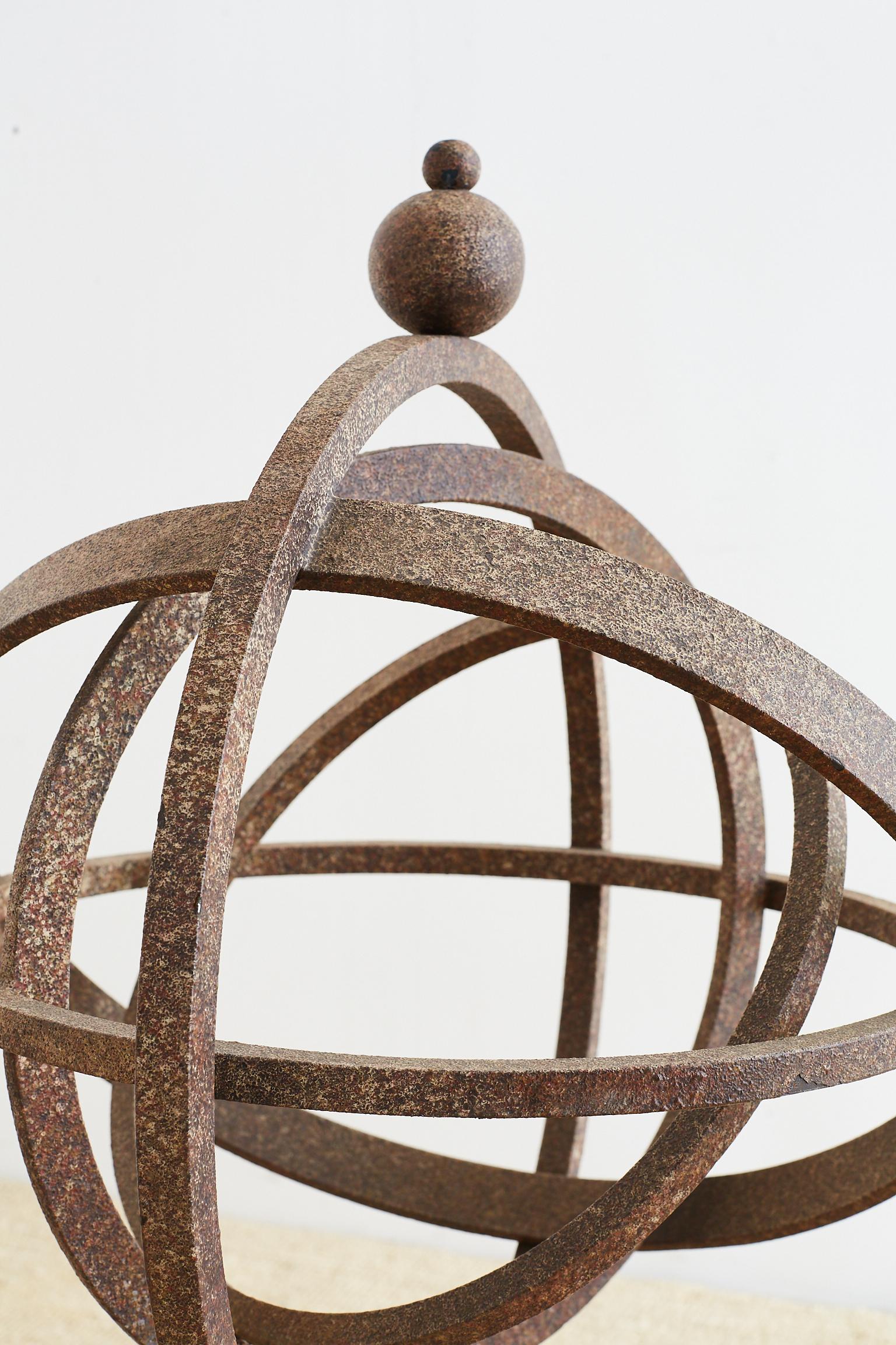 Decorative iron garden armillary sphere or garden globe on stand. Features a non-turning set of rings on a ring stand with round feet and topped with a round finial. The iron is coated with a distressed patinated finish. Heavy and solid measuring 42