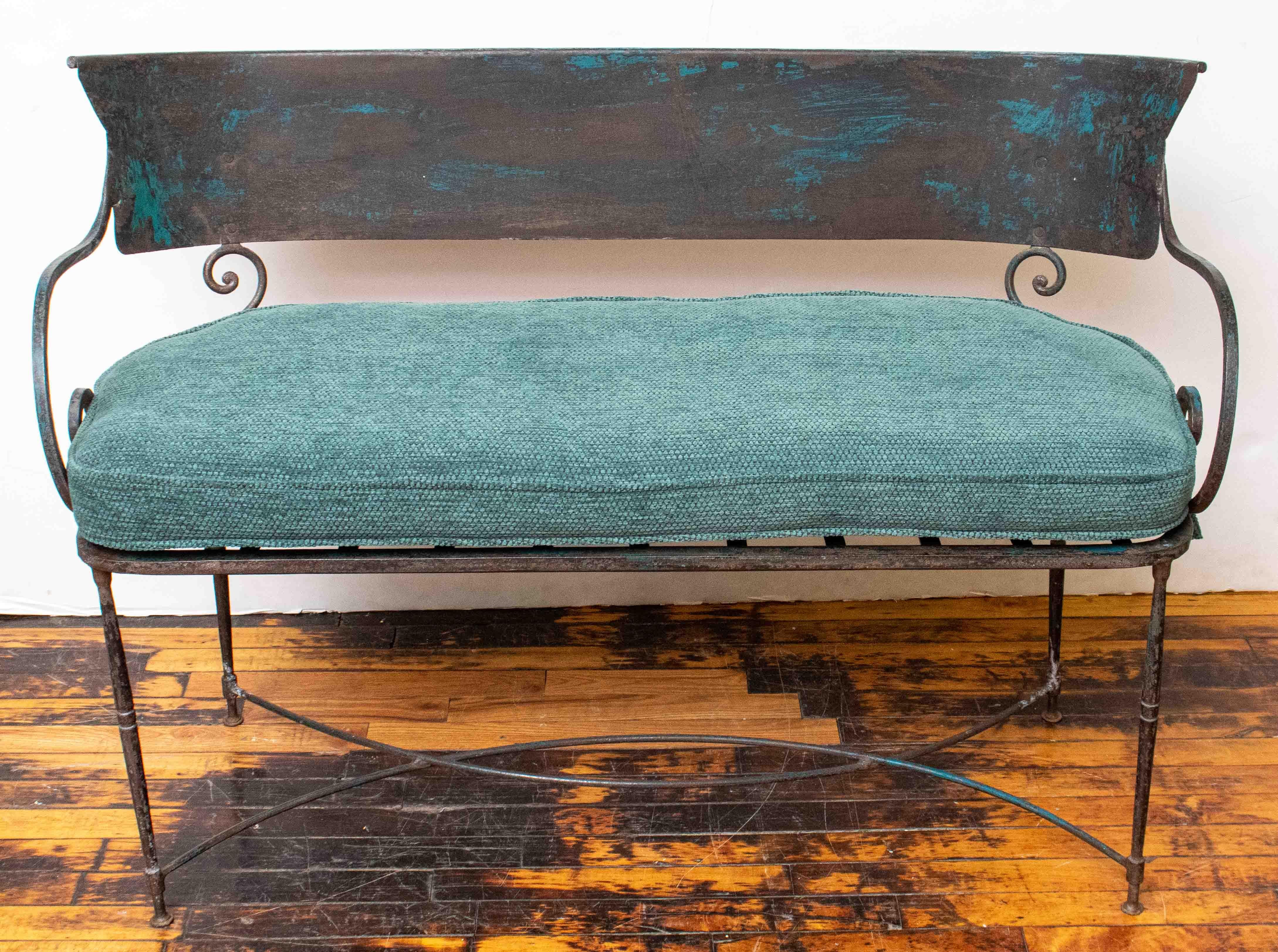 Beautiful iron garden settee with traces of original turquoise paint on the metal. A custom handmade cushion has been added that is upholstered in a deep blue-green chenille. There are metal straps under the cushion. Made in France - needle point