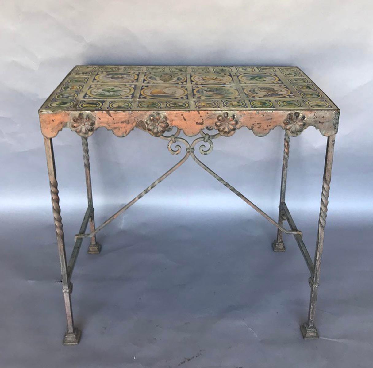 Rustic tile inset garden table with iron legs and stretcher. Remnants of light pink and grey pant on base. Glazed ceramic tiles.