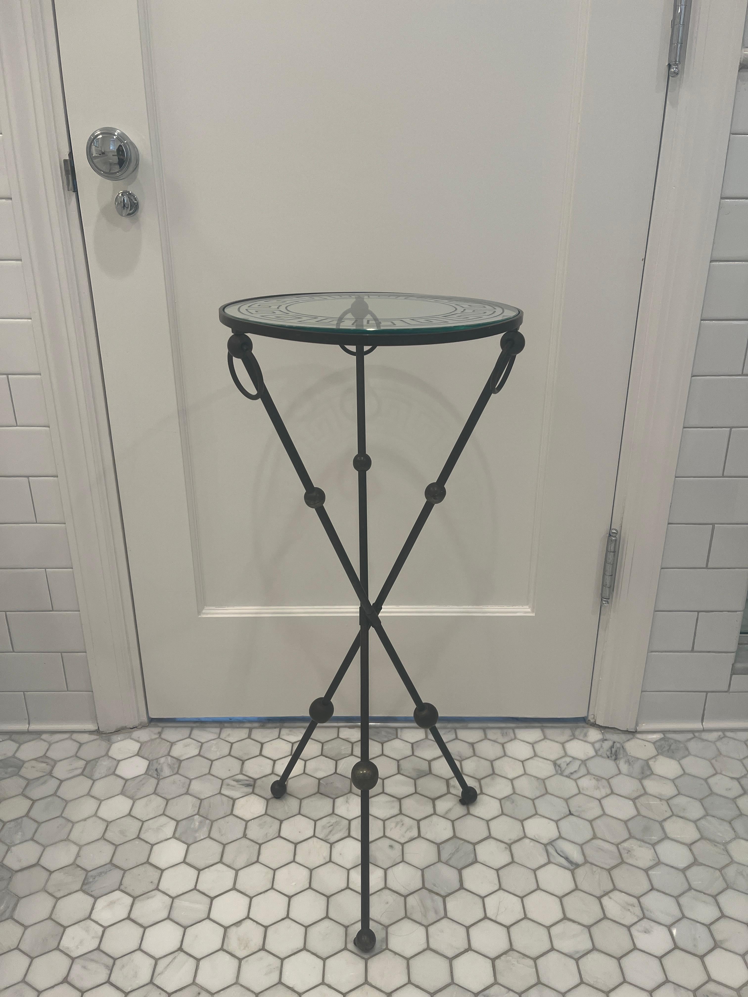 1930s Art Deco French black iron Gueridon table with tripod base and glass top etched with a Greek key motif border. Each leg of the tripod base has sphere details/feet and rings at the top. 