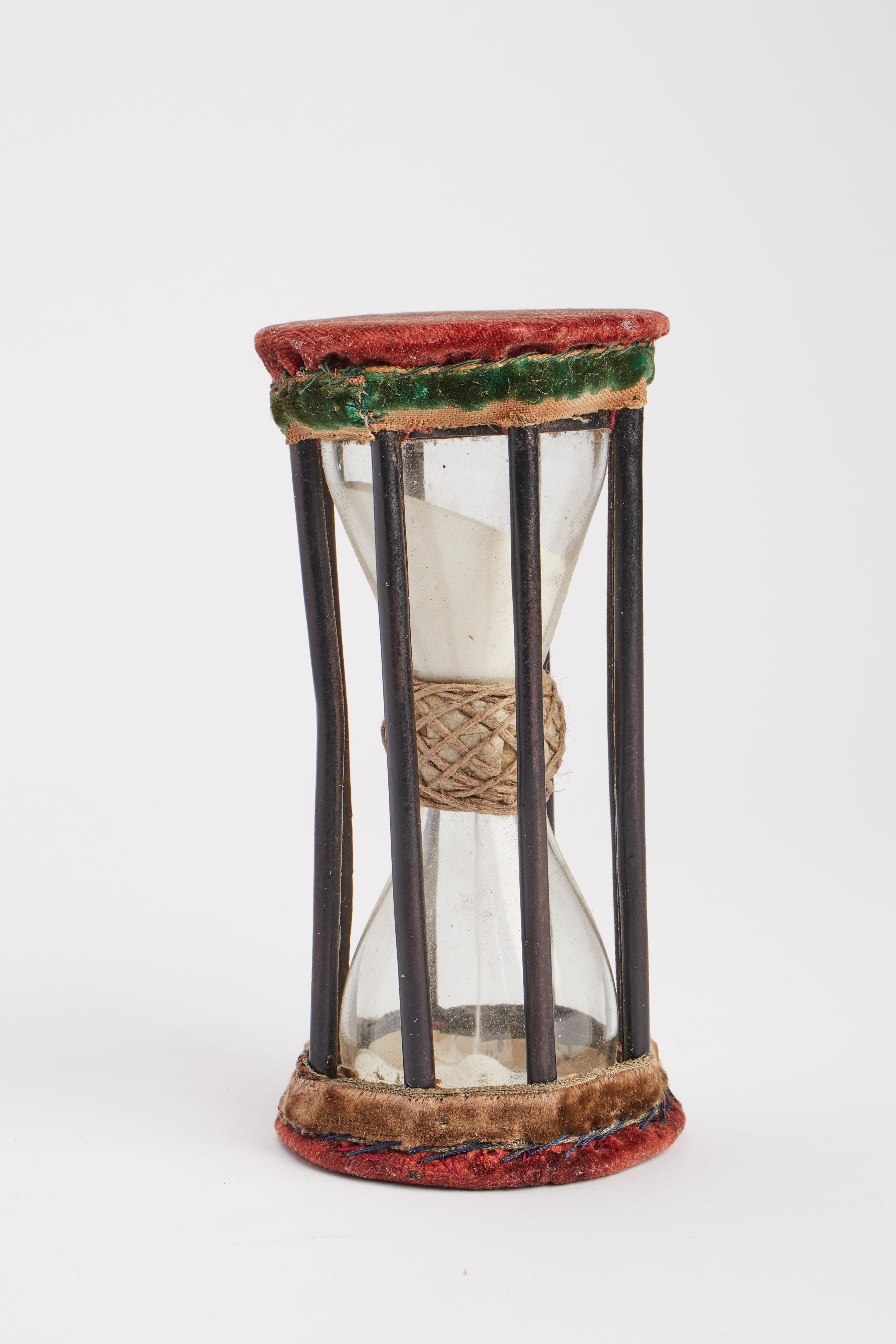 The hourglass cage displays octagonal bases, dressed in a red velvet cushion. Eight smooth iron columns complete the cage. Inside the glass bulbs joined in the center by a ring of fabric and rope. Germany early 1700s.