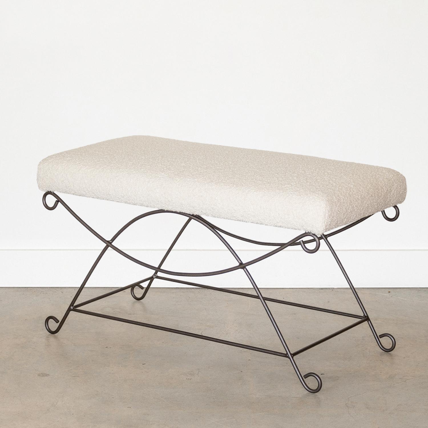 Beautiful iron bench with curved and looped base painted in a matte black finish. Rectangular cushioned seat upholstered in a bouclé fabric or can be COM. Multiple available, sold individually.
