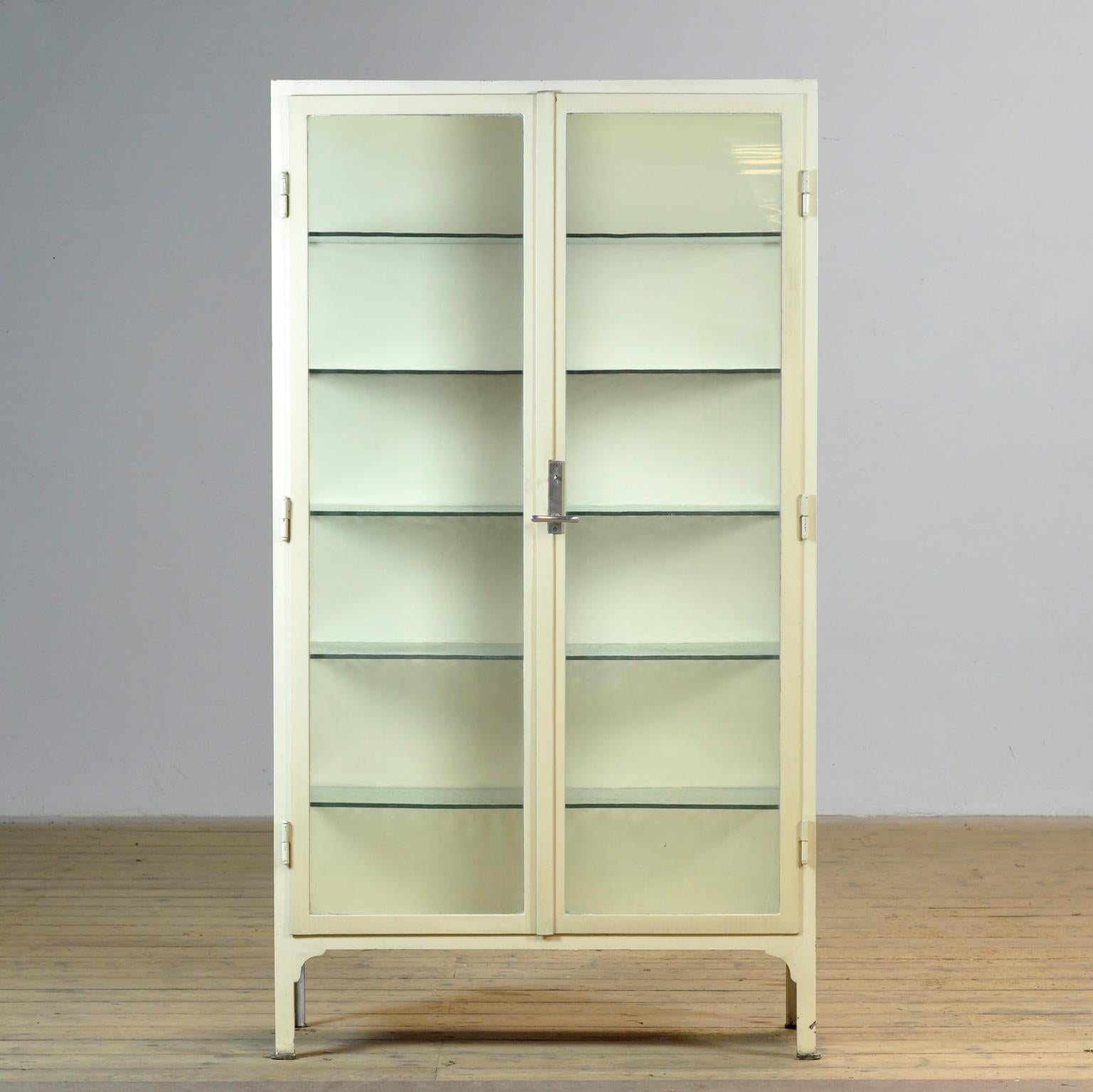 Gabinete médico de los años 30, procedente de Hungría. Este mueble rezuma carácter y artesanía, con su robusto armazón de grueso hierro y su original cristal antiguo. La auténtica cerradura y el elegante tirador son totalmente funcionales y dan al