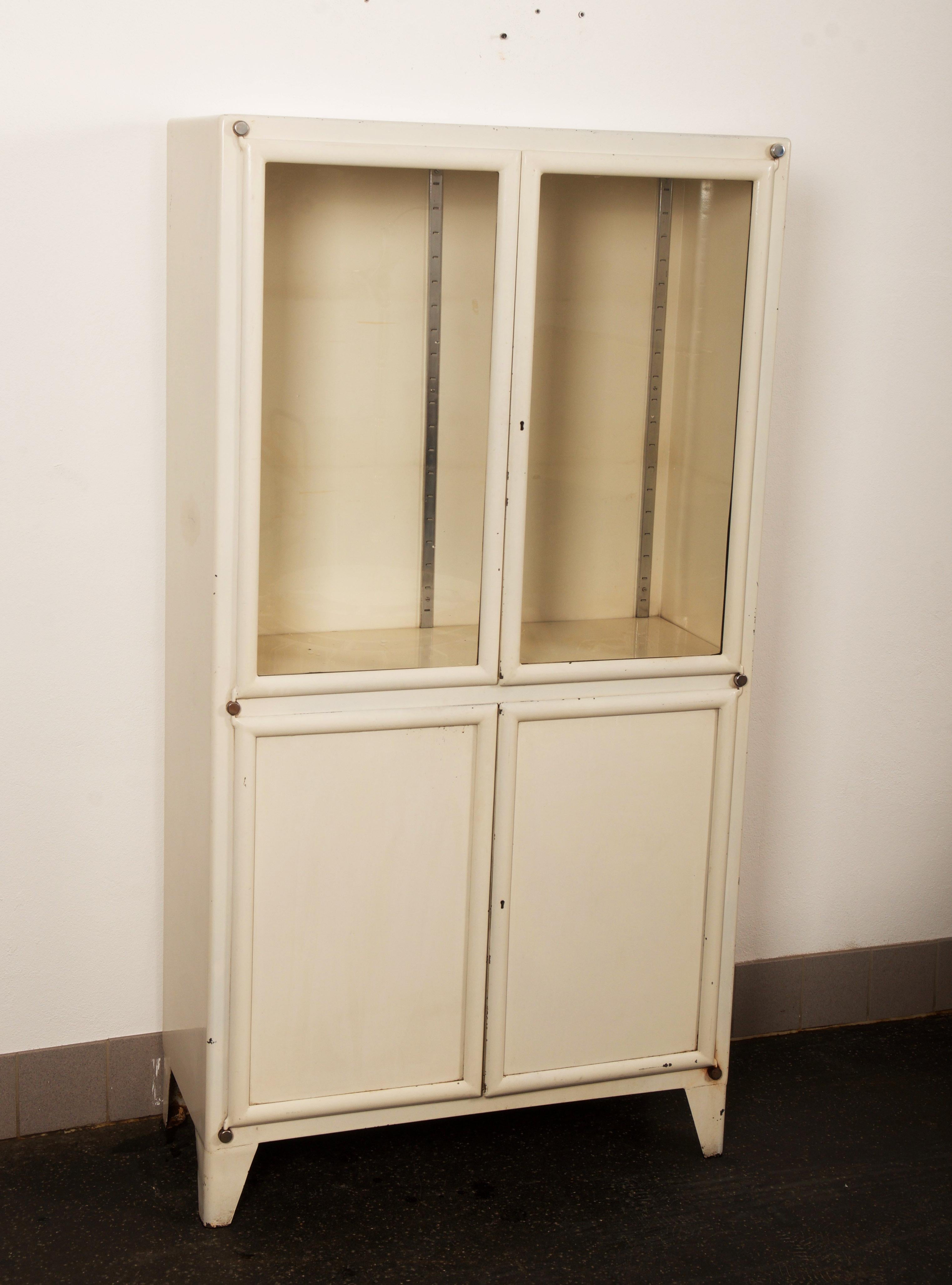 Steel painted with each two glass doors and steel doors. Made by Kovona in the late 1940s-early 1950s in former Czechoslovakia.
Used condition, missing glass shelfs and original key.
 