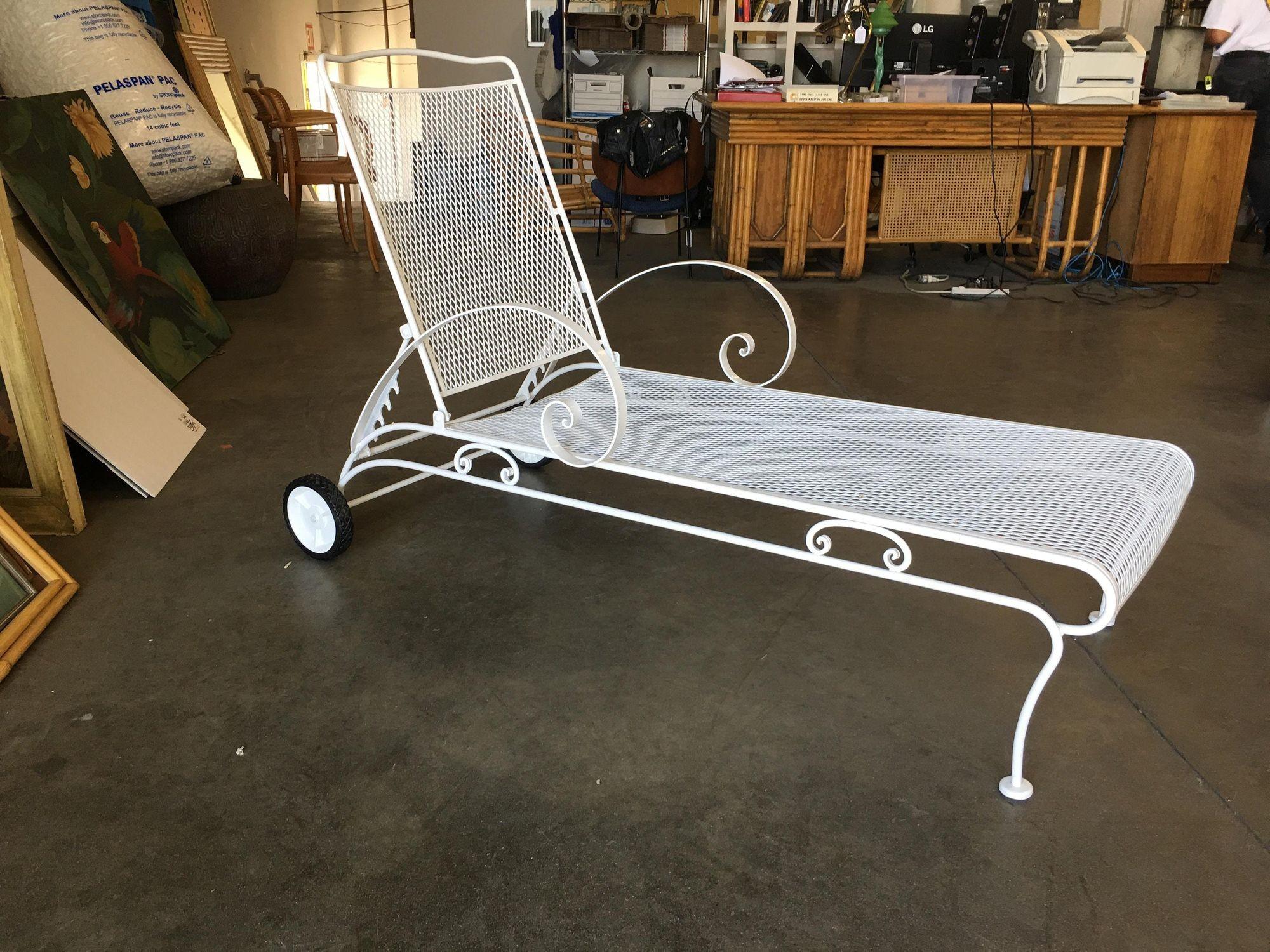 White painted iron outdoor / patio chaise lounge, produced in 1950 by the Woodard Furniture Company. This comfortable and stylish vintage chaise lounge features a fully adjustable reclining back and back wheels for easy moving with large scrolling