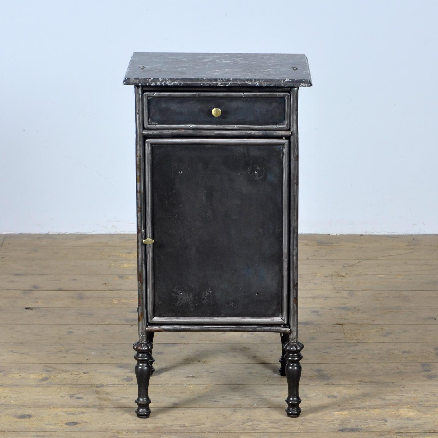 Bedside table made of iron with a marble top. The cabinet has brass knobs on the drawer and door. Beautiful cast iron legs. Stripped to the metal and polished. circa 1900.