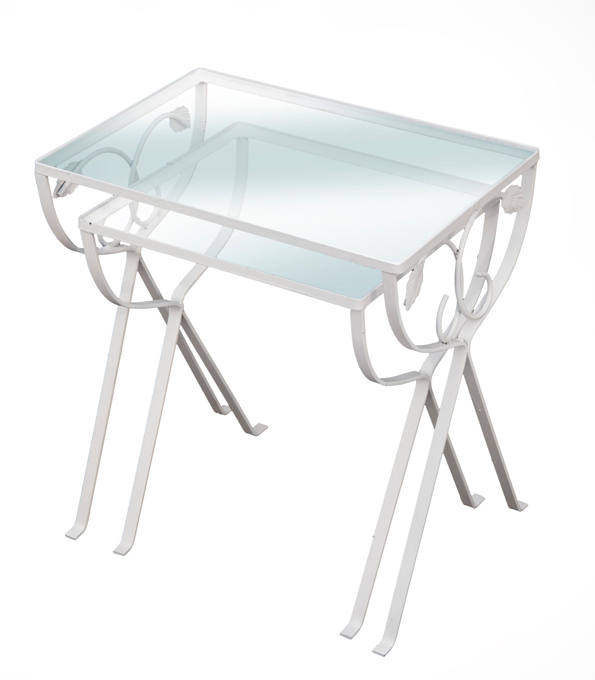 Wrought iron nesting tables, white with glass tops.
Vintage glass topped stacking tables have a traditional curved vine and leaf pattern. Painted in white. Strong and sturdy in a versatile size designed for patio use, but a nice accent for sunroom