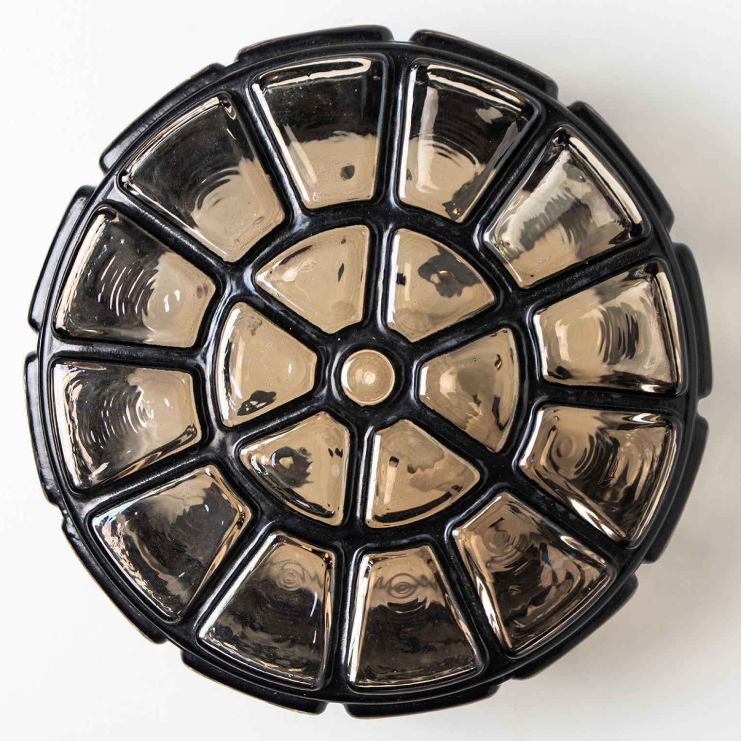 A wonderful round iron flush mount, circa 1970, made by Glashütte Limburg, Germany.
With hand blown smoked glass on brass base and a cage-like structure in iron. Illuminates beautifully.
Can either be mounted on the ceiling or on a wall.

Please