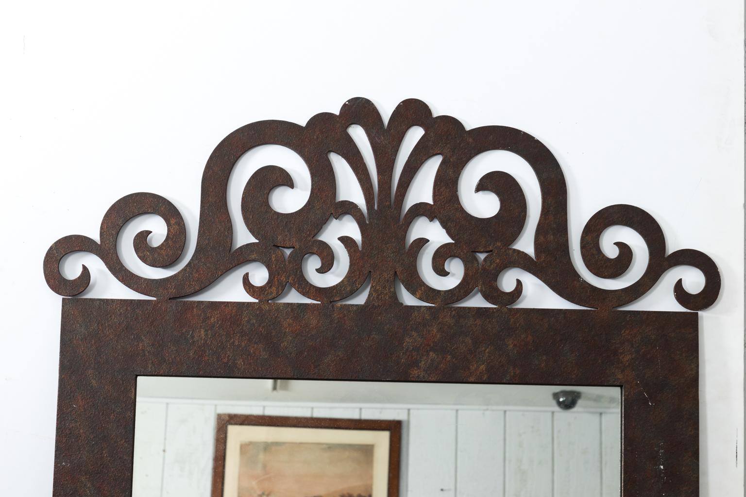 Continental style iron mirror with scrolled crest that features a center palmette. The iron itself is in a distressed finish.