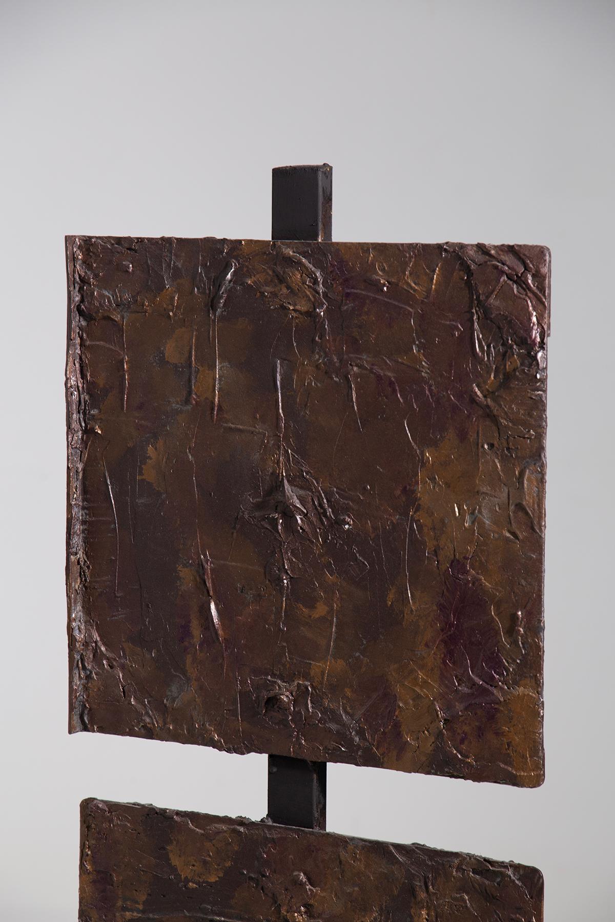 This modern sculpture by Aldo Guarnieri commands attention with its austerity and visual complexity. Crafted with a mixed technique, the piece consists of two overlapping square panels, mounted on a metal structure that suspends them in mid-air,