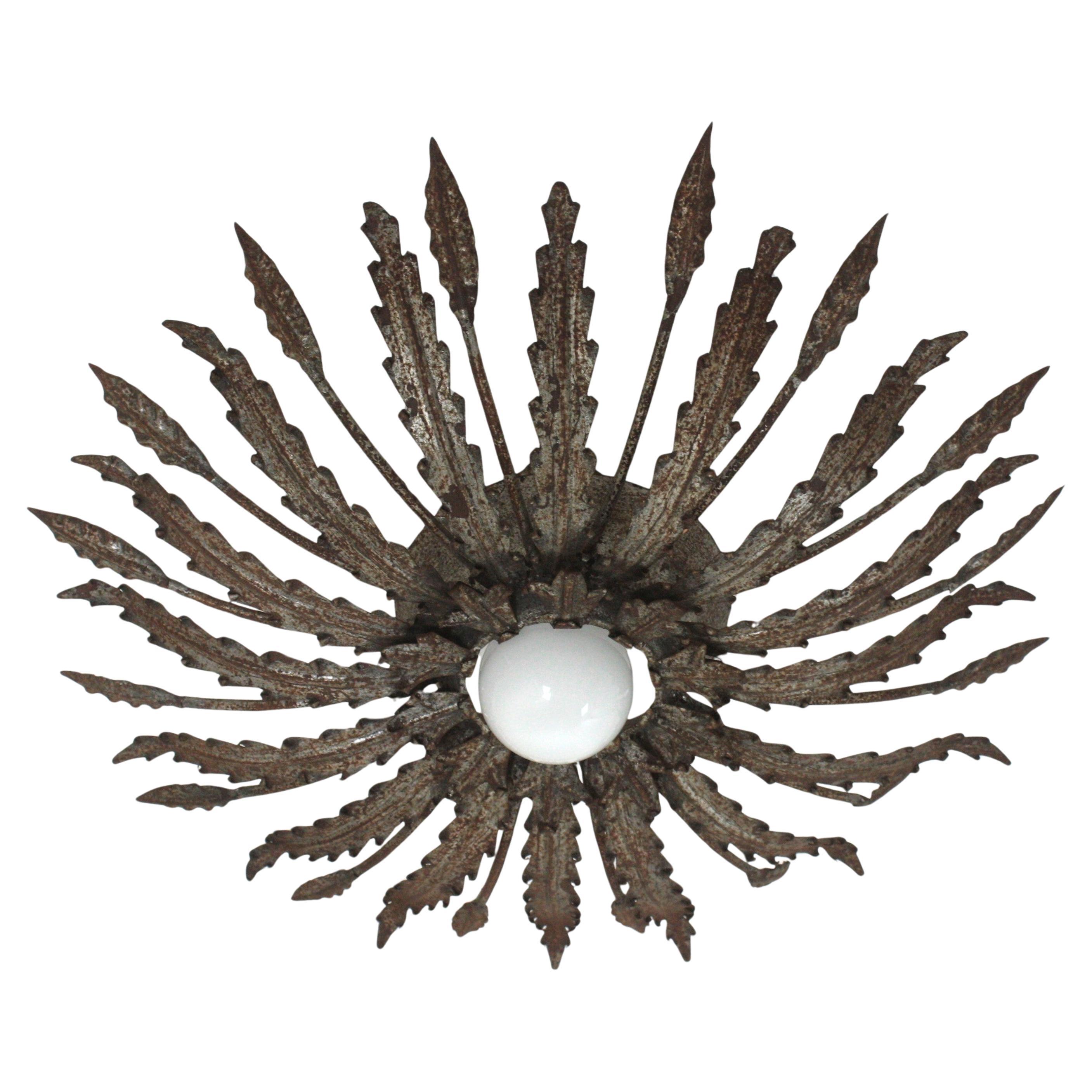 Brutalist Foliage Sunburst Light Fixture in Rusty Iron, Spain, 1950s.
This Brutalist hand-hammered iron sunburst flush mount has leafed design with alternating leaves with different shapes surrounding the central light. 
It has a terrific aged