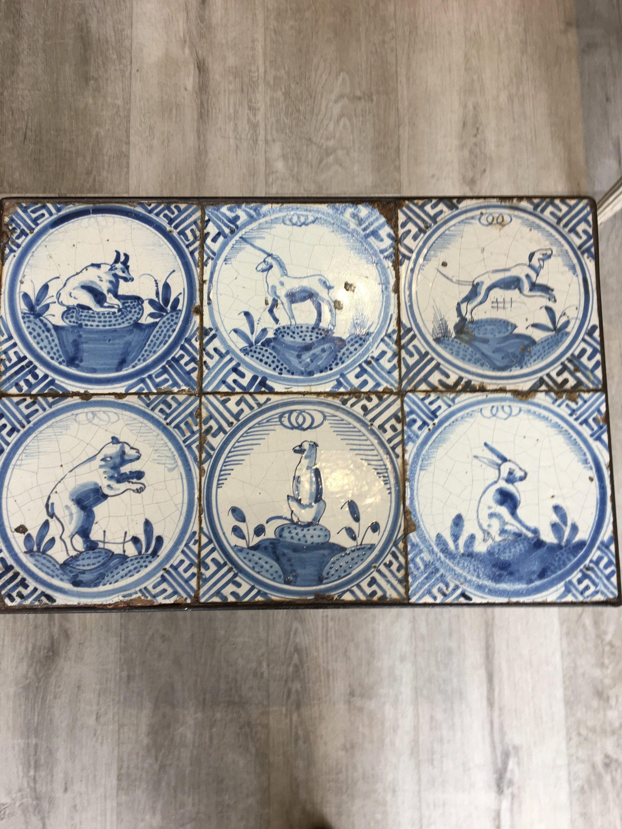 Small iron side table having six 17th century delft tiles featuring rare animal tiles: a rabbit, bear, two dogs, a goat and a unicorn.
