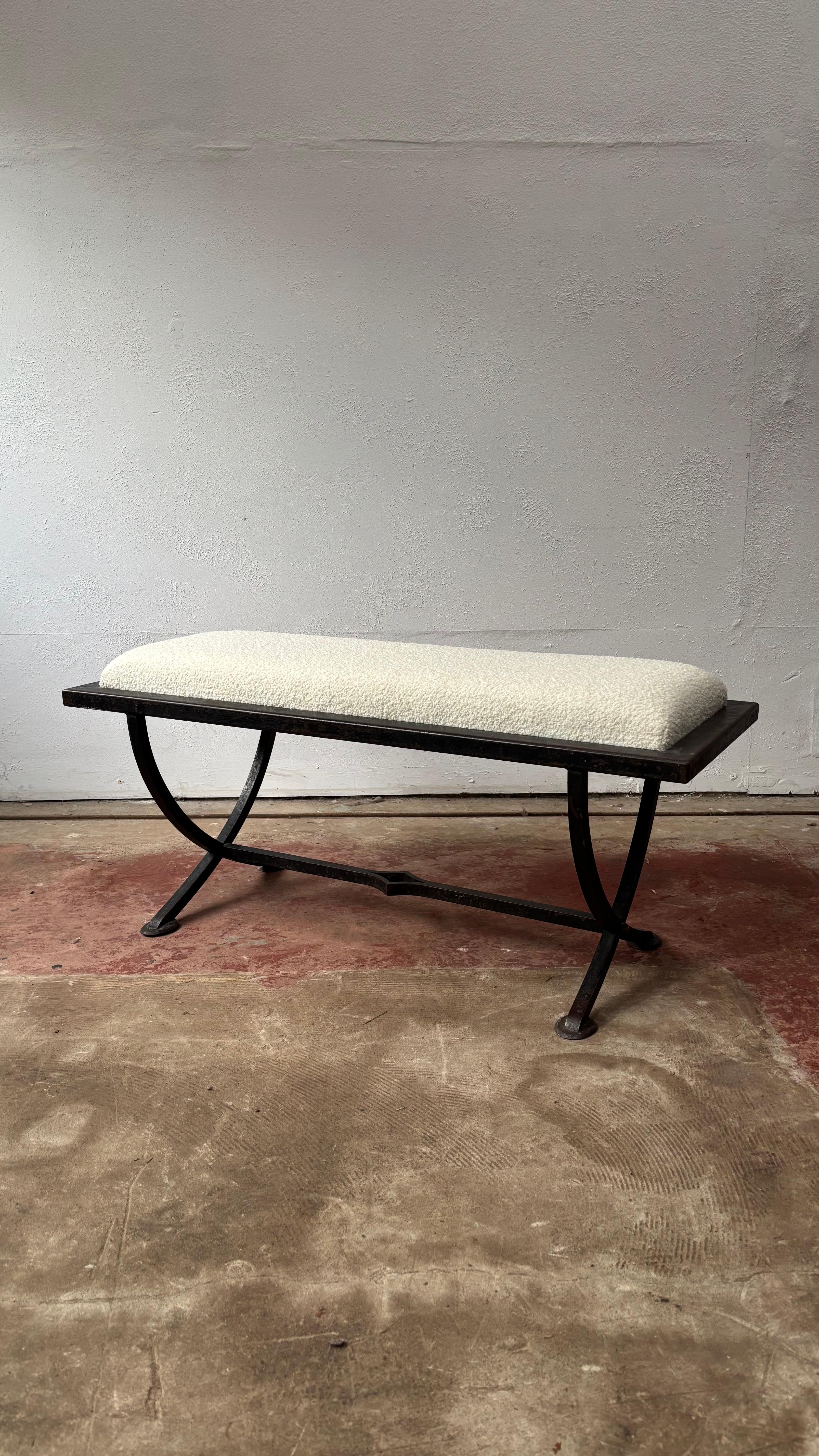 This elegant French iron bench was made by skilled European craftsmen using traditional iron working techniques. It features gracefully curved legs X-frame legs and a central stretcher with a decorative central diamond detail. The hand forged iron