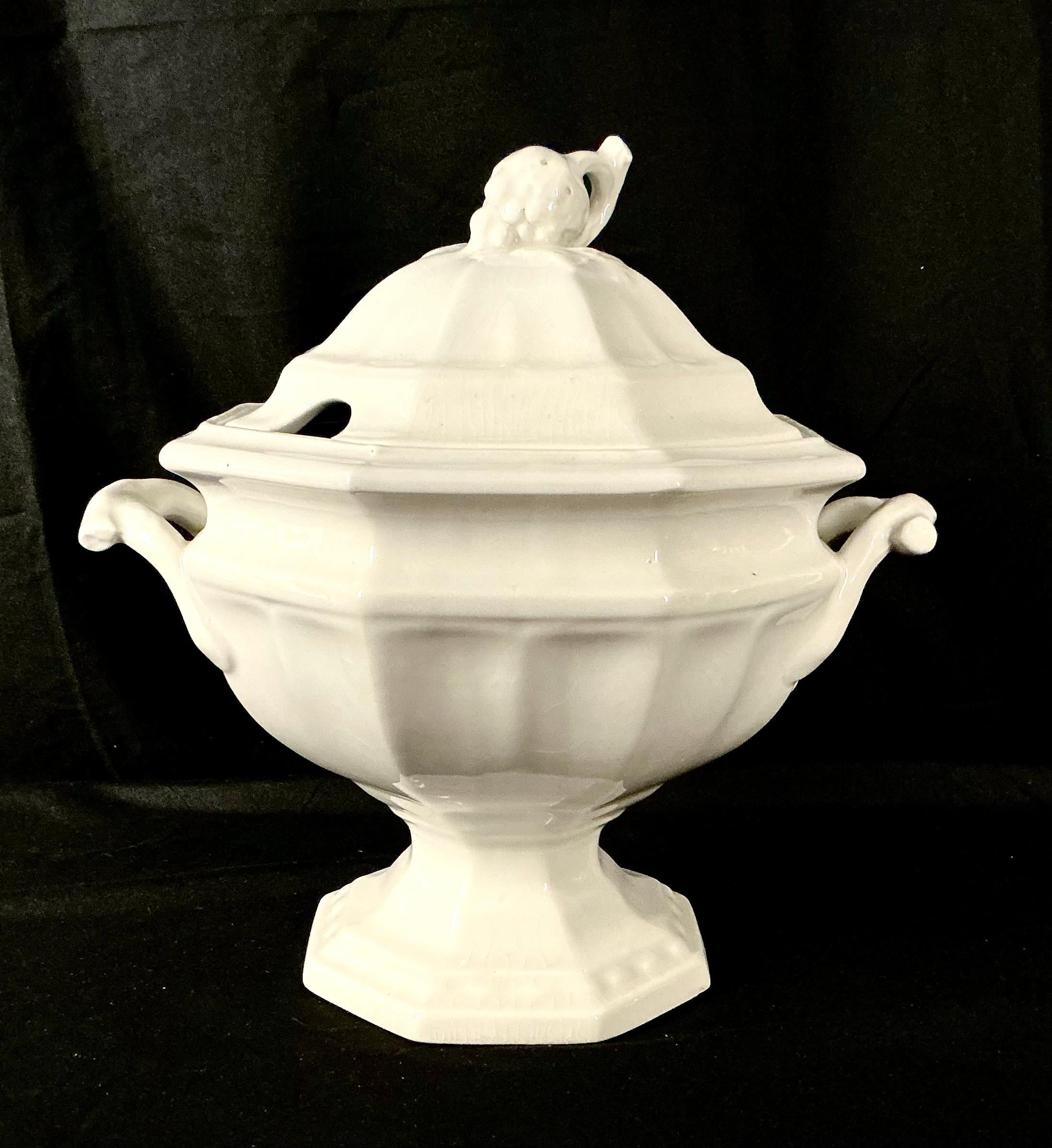 20th Century Ironstone Soup Tureen With Lid. Tureen features a beautifully scalloped body and graceful double scrolled handles, with a striking grape cluster finial on domed lid. Tureen rests on a sturdy pedestal base for a refined presentation. Top