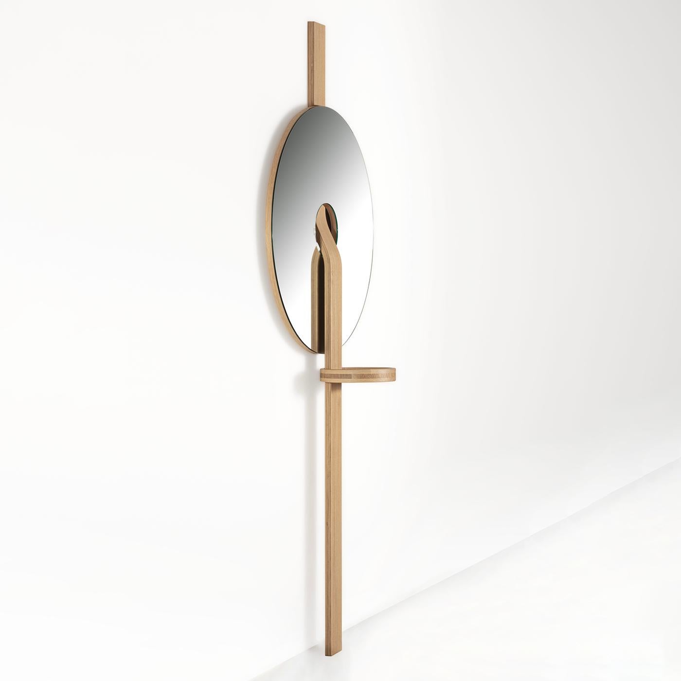 A natural addition to contemporary decors, this wall mirror stands out for its sculptural aesthetic. A slightly curved structural band in solid durmast pierces the mirrored glass disk, creating a combination of unmistakable geometric inspiration. A