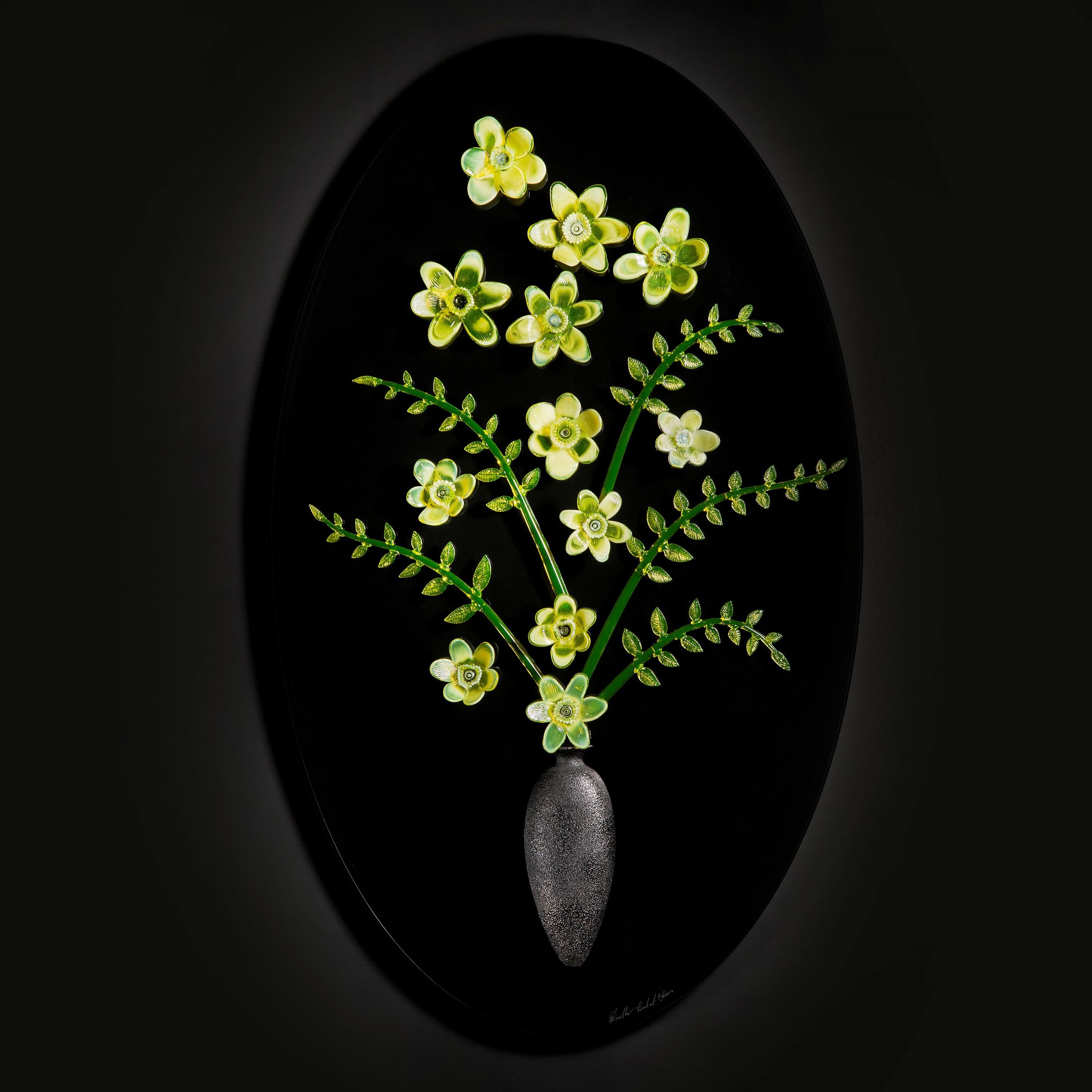Irradiant Bloom VI is an oval sculptural wall mounted artwork by the British artist and Blown Away II series winner, Elliot Walker. The artwork features hand-sculpted uranium flowers with a bisected black vase that is bonded to the back. The various