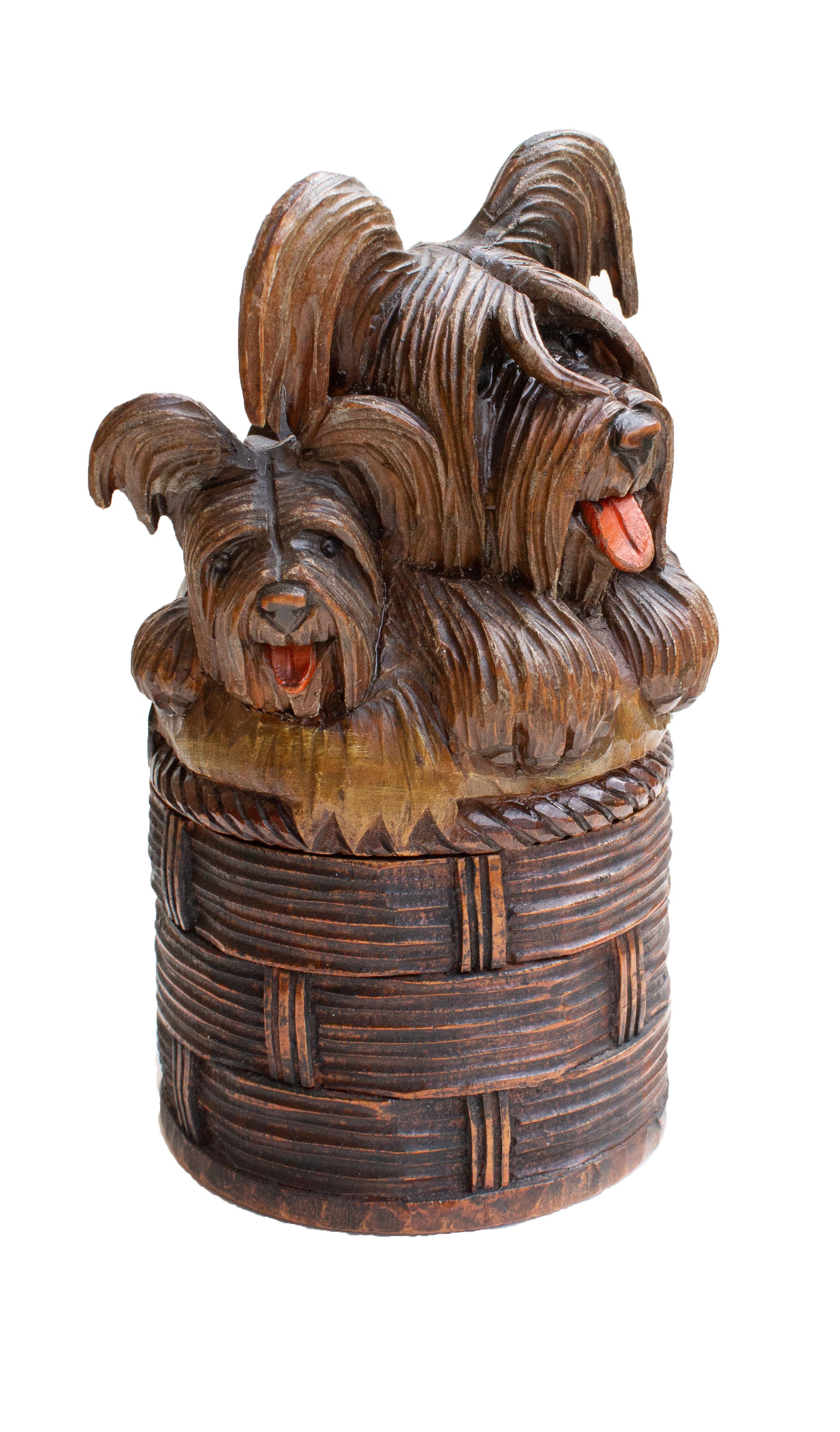 This adorable box, shaped like a woven basket, is crowned with three lively carved terriers, each with expressive features, shining glass eyes, and a lovingly detailed coat. The craftsmanship and style strongly echo the classic Black Forest carvings