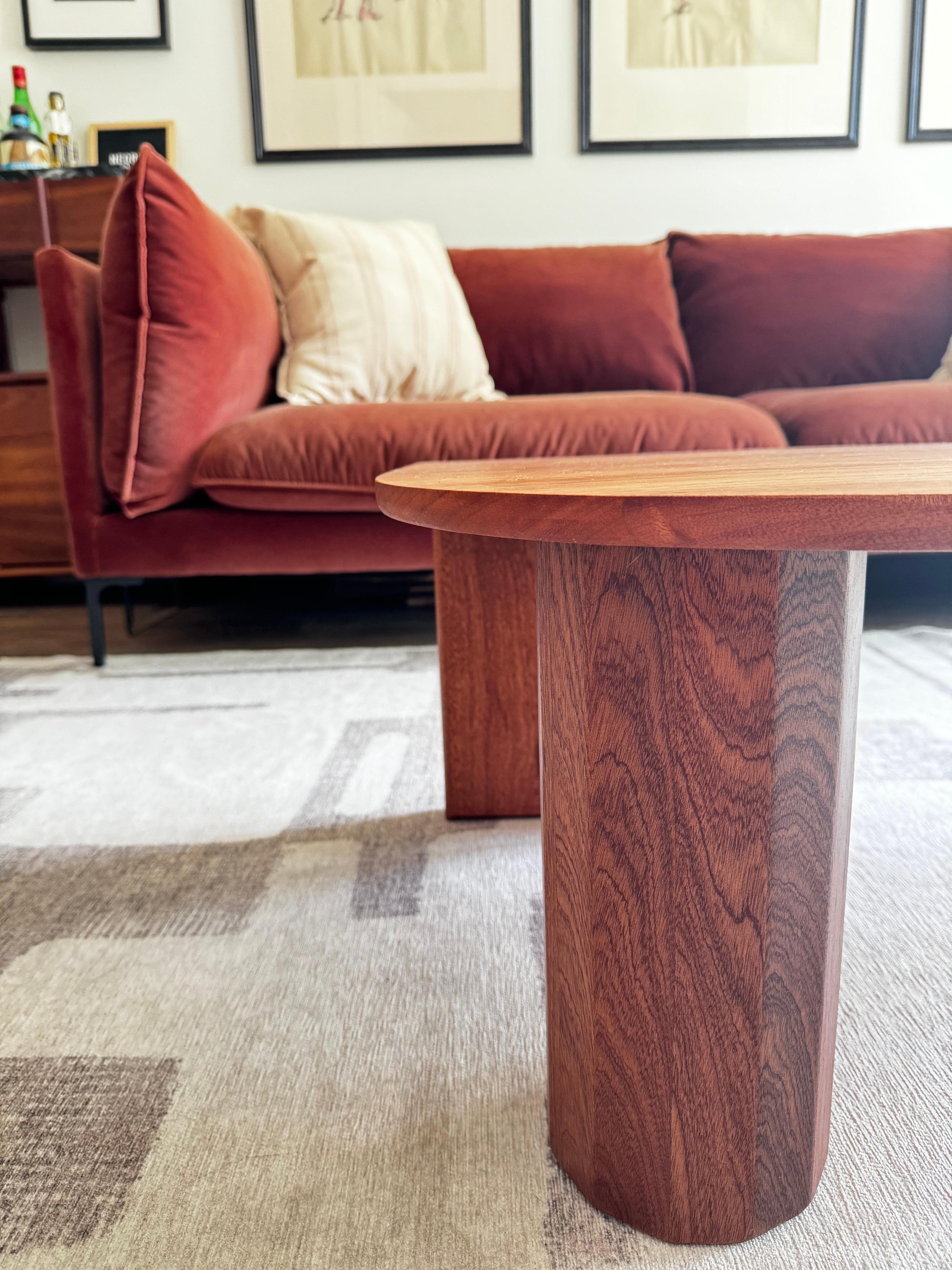 Cette table basse personnalisée, disponible en chêne, acajou, érable ou noyer, est un mélange étonnant d'artisanat et de design contemporain. Dotée de bords légèrement arrondis et de pieds ovales robustes, la table met en valeur le grain et le