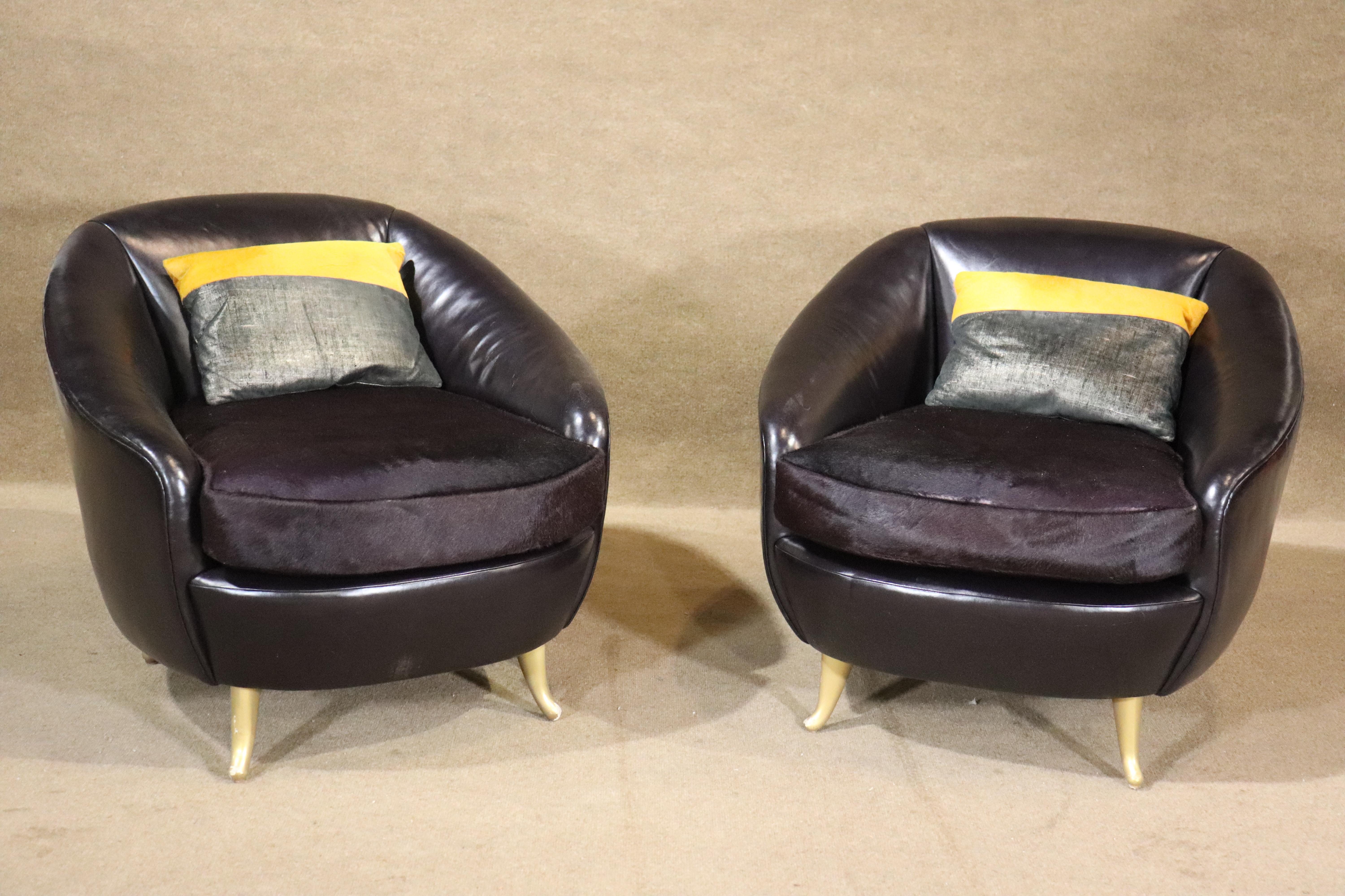 Pair of mid-century style tub chairs in leather and hide. Accented with low brass legs. Round barrel back shape frame in leather with matching color hide seats. 
Please confirm location NY or NJ
