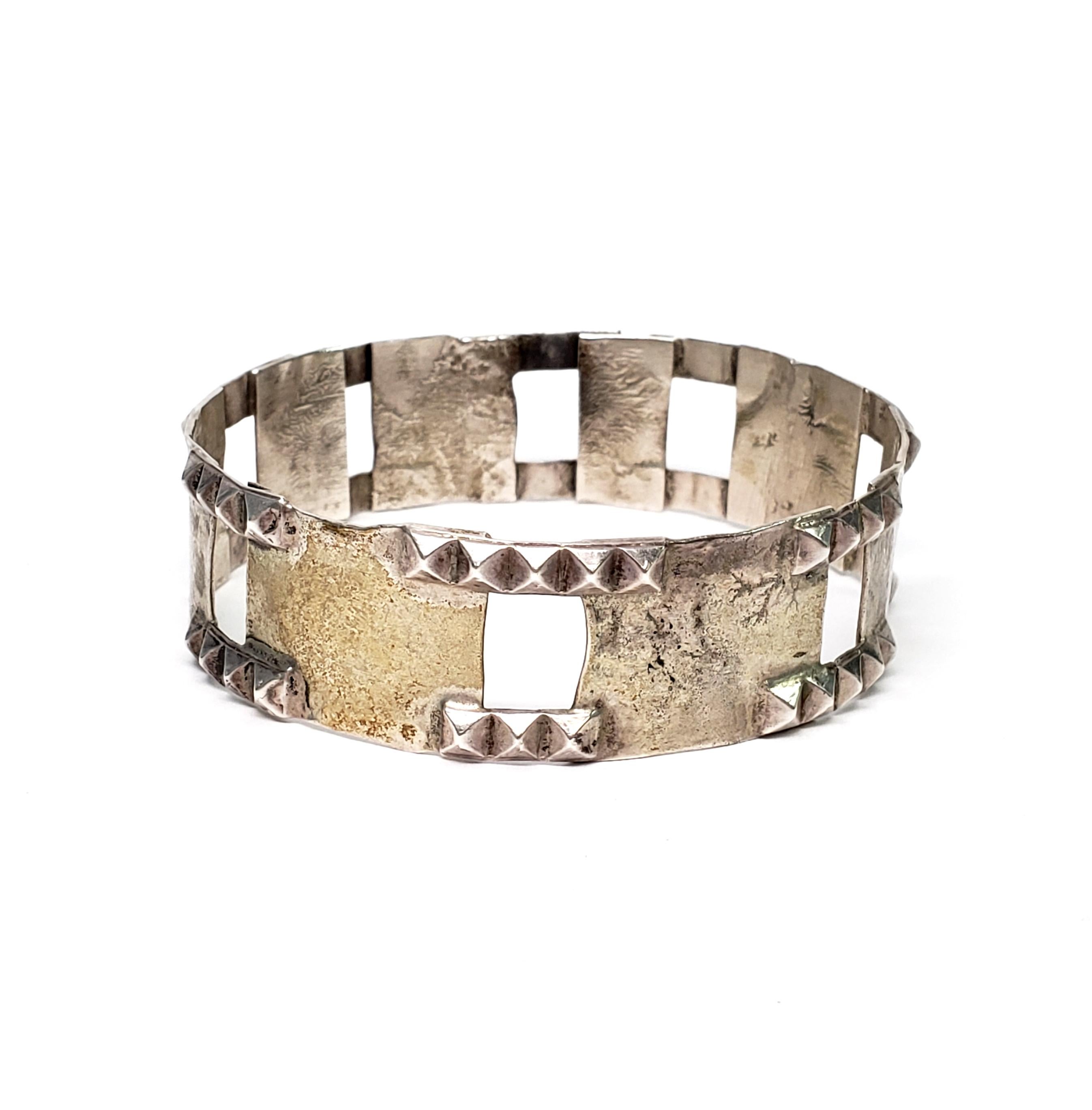 Vintage Isaac Cohen sterling silver bangle bracelet.

Modernist design features studded edges, rectangular cut-outs and textured panels. From Stockholm, Sweden, circa 1969.

Size 8, 2 5/8